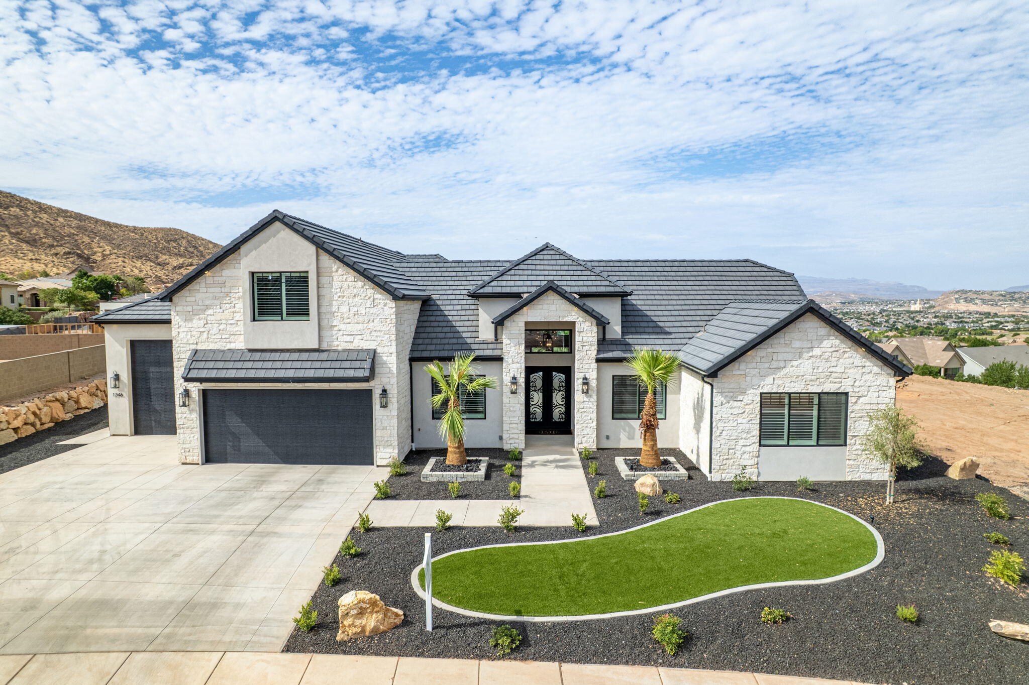 Welcome to an extraordinary custom home where luxury, design and views collide. Double iron doors and a stunning wood and tile entry set the tone from the moment you arrive. The showstopping great room features soaring 14-foot ceilings, a floor-to-ceiling white stone fireplace, and disappearing pocket doors in both the great room and dining room for true indoor/outdoor living. The kitchen is fully loaded with Taj Mahal quartzite countertops, Wolf double ovens and cooktop, Sub-Zero refrigerator, ice machine and reverse osmosis water filtration, all flowing seamlessly on gorgeous white oak engineered hardwood floors. The home gym welcomes you with wall-to-wall mirror, heavy duty rubber mat flooring and mini split. The primary suite offers a cozy fireplace, garden tub, walk-in shower, dual sinks and a spacious walk-in closet. Outside is an entertainer's dream! 18x35 heated Gunite pool, raised hot tub, outdoor kitchen with gazebo, paver patio and sweeping views framed by mature palms. Built with 2x6 construction for superior quality by Bird Homes The 4-car garage with 38-foot bay features epoxy flooring and insulation, plus the home features a built-in speaker system. Add HVAC zoning, a rooftop deck and panoramic views and no HOA and this home checks every box. Minutes from Costco, the mall, SGU airport and the upcoming Paseo shopping district in the Crimson Cliffs High School boundaries.