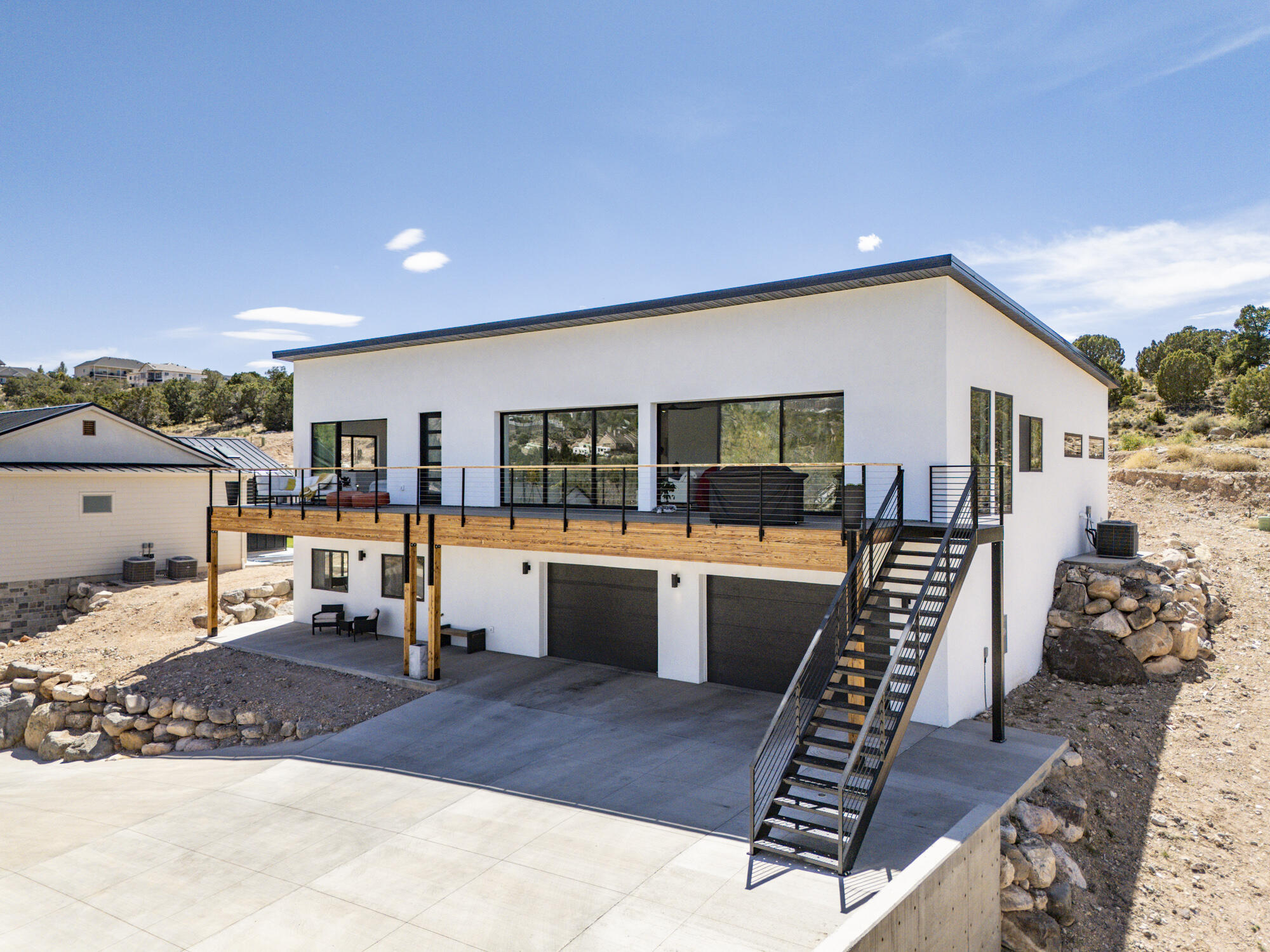This stunning single-family contemporary residence offers 3,400 square feet of living space, including 2,600 on the main level and an 800-square-foot basement. The property features five bedrooms, three full bathrooms, and a spacious 4-car garage with a basement entry. The exterior showcases a modern design with a metal roof and a deck, perfect for outdoor gatherings. Inside, high ceilings, walk-in closets, granite countertops, and a dedicated work area create a luxurious and functional environment. An attached ADU with two bedrooms, a kitchen, and shared utilities adds versatility, ideal for extended family or rental income. Additional features such as a laundry room, energy-efficient windows, and smart home technology make this property even more appealing for modern living.