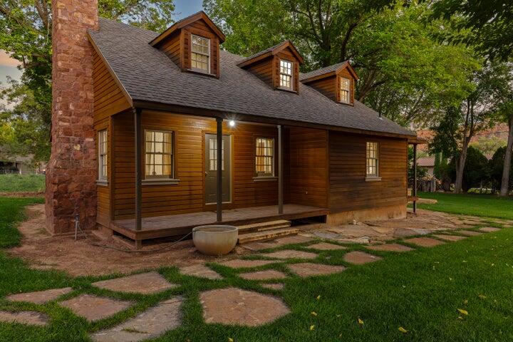 Welcome to 127 W. Main Street, a breathtaking 1944 gem in the Rockville Townsite. Offering stunning mountain views and unparalleled access to Zion National Park, this 3-bed, 2-bath, 1,838 sq. ft. home is a true work of art.
The property's pedigree is unmatched: meticulously remodeled, preserved, and furnished by the renowned Werner Weixler of the F. Weixler Company. Known for over 40 years of mastery in custom furniture and interior design, Weixler transformed this property into an exquisite blend of vintage character and luxurious modern comfort, showcasing an uncompromising standard of bespoke craftsmanship.
Set on a flat 0.23-acre corner lot, the home features classic wood siding, a covered deck, and custom sandstone-furnished grounds with an automatic sprinkler system for the lawn and old-growth trees. Wake up to world-class, breathtaking red-rock views right from your beautifully landscaped yard--the perfect setting for morning coffee or evening entertaining.
Inside, the main level hosts the primary suite, a bright kitchen with freestanding appliances, and a cozy living room anchored by a rustic wood-burning fireplace insert. Upstairs is a spacious loft bedroom with two queen beds and charming dormer windows. A partially finished basement offers laundry facilities and ample storage. 
This turnkey home is move-in ready, coming fully equipped with custom window coverings and expertly curated designer furnishings (fweixlerco.com). Enjoy the quiet, serene atmosphere of historic Rockville while remaining just minutes from Springdale and the gates of Zion.
Whether you seek a primary residence rich with history, a luxury Zion retreat, or a basecamp for Southern Utah's outdoor recreation, this home is a must-see. Schedule your showing today and own a curated piece of Utah Pioneer history!