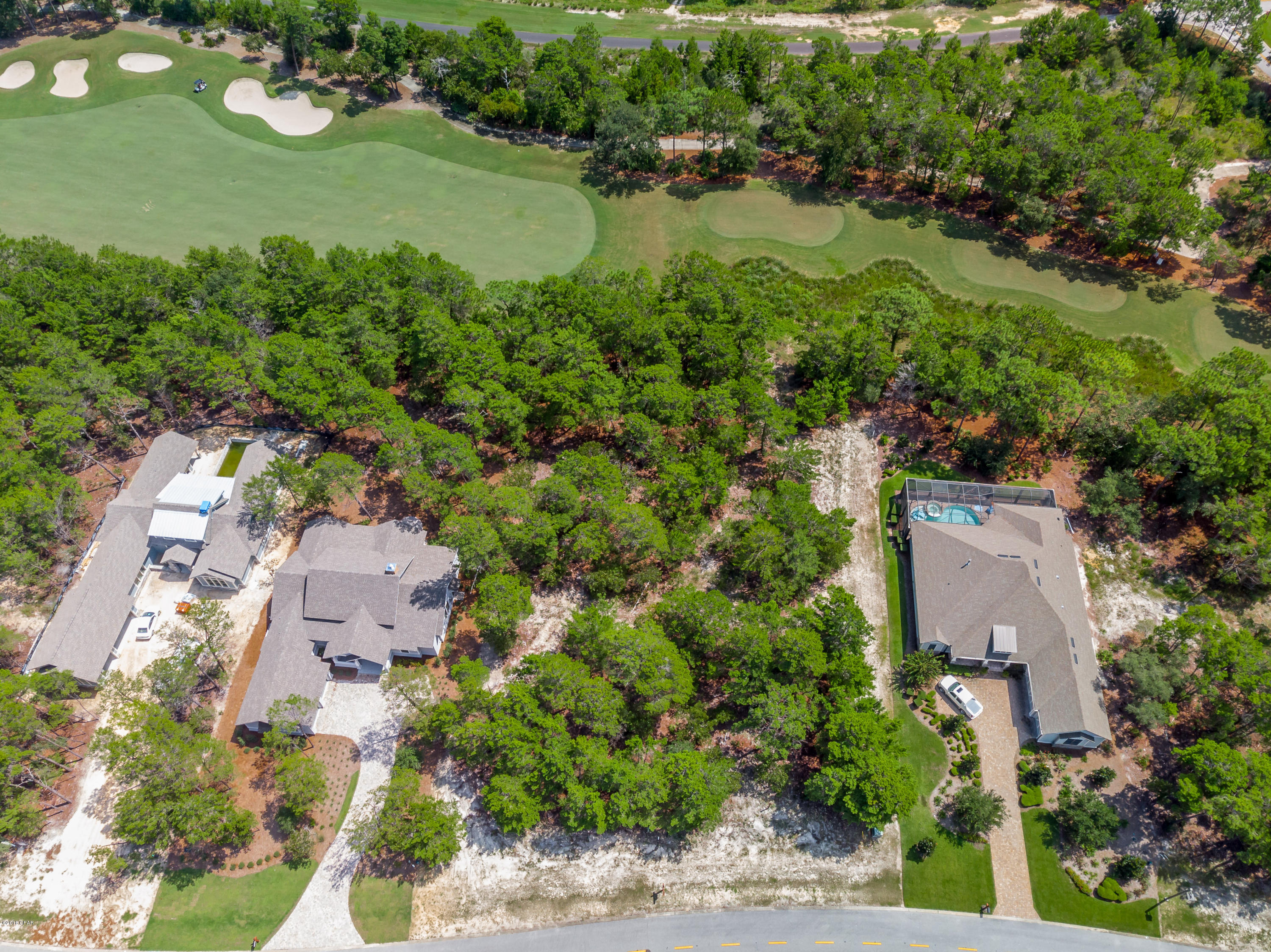 : LOT & HOUSE PLANS: This beautifully wooded lot is located on the 10th fairway of the renowned Shark's Tooth golf course. The price of this lot includes an architectural home design that has already been approved by the Wild Heron ARB. The approved design is a 3 bedroom, 2 bath home with 2,438 sq. ft. of heated and cooled space, screened pool and lanai. Homeowner amenities include gated entrance, pools, hot tub, fitness center, boathouse with canoes & kayaks, fire pit, picnic area, boardwalks and walking paths. Wild Heron is conveniently located between Pier Park and the entertainment and dining along 30A. Setbacks: sides 7.6ft front 35' back 40'