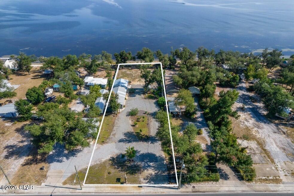 Enjoy exceptional waterfront living on this stunning .75-acre property featuring 90 feet of beautiful East Bay shoreline in the heart of Bay County, Florida. This unique property offers approximately 800 square feet of heated and cooled studio-style living space, perfectly designed to capture breathtaking water views through expansive picture windows and showcase unforgettable sunrises each day. The home features a spacious, attached, oversized two-car garage and a large, welcoming, open pole barn-style front porch ideal for relaxing while taking in the scenic bayfront setting. Privacy fencing offers the perfect retreat to take in the views, while a newer sprinkler system keeps your garden creations maintained. This property offers an unbeatable lifestyle location. Sidewalks provide easy access to two nearby parks, including a public pier, walking trails, a large wooded playground, and a Frisbee golf course--all within walking distance. Directly across the street, enjoy a wide variety of restaurants, cafes, bakeries, coffee shops, and diverse dining options, including Thai, sushi, Italian, and more. Nearby is a full-service marina that offers charter fishing excursions, waterfront dining, a tiki bar, and social gathering opportunities, creating endless recreational possibilities right outside your door.
Zoned Mixed-Use, this property presents incredible opportunities beyond personal enjoyment. Whether you envision a private waterfront retreat, short-term rental investment, multifamily development, townhomes, apartments, or up to 12 units, the development potential is substantial. Its prime frontage along Tyndall Parkway, with thousands of daily passing vehicles, also makes it an outstanding candidate for retail, hospitality, restaurant, or other commercial opportunities. Rarely does a property combine waterfront beauty, walkable amenities, flexible mixed-use zoning, and exceptional development potential in one offering. Whether you're seeking a dream home, income-producing investment, or large-scale development opportunity, this East Bay property delivers endless possibilities. Don't miss this rare chance to own one of Bay County's most versatile waterfront properties. Contact your favorite Realtor today to schedule a private showing or learn more. 
Some photos have been modified by AI. Buyer to verify any information deemed important.