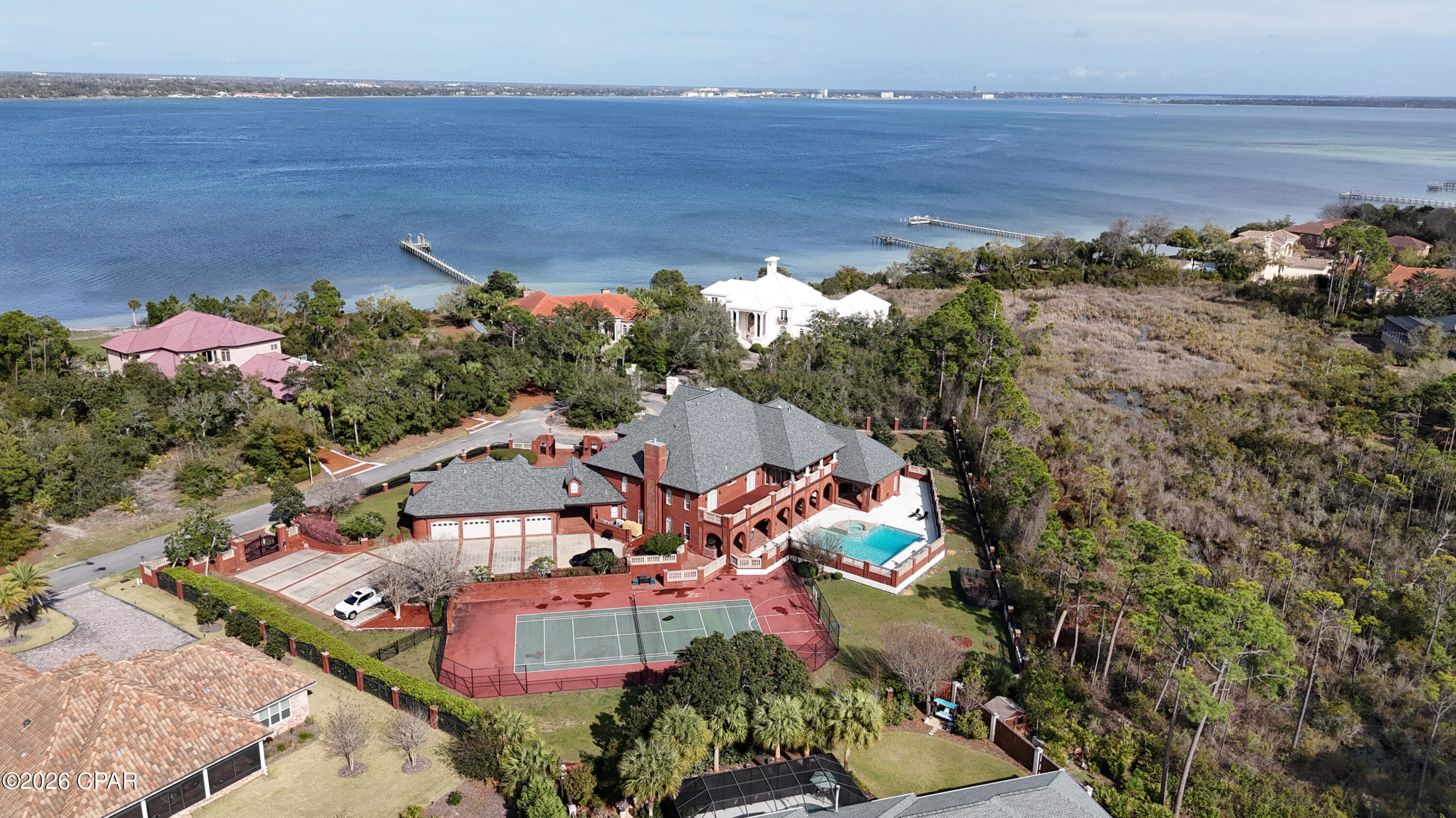 Why settle for a beach house when you can own a fortress?

3703 Preserve Bay Blvd | Estate Living in The Preserve

Located within the prestigious gated community of The Preserve, this extraordinary 12,200 sq. ft. estate sits on approximately 1.6 acres and offers a rare opportunity to own one of Bay County's most remarkable homes. Combining impressive architectural scale with timeless craftsmanship, this property was designed for both elegant living and exceptional entertaining.

From the moment you arrive through the gated brick entrance and circular drive, the home makes a lasting impression. The grand brick façade, dramatic arched entryway, and classic dormer windows create a striking presence that reflects the quality and attention to detail found throughout the property.

Inside, the home showcases Italian marble, Brazilian mahogany hardwood flooring, and premium granite and marble finishes that add warmth and sophistication throughout the living spaces. Soaring 11-foot coffered ceilings and 8-foot interior doors create an atmosphere of openness and light, while lead crystal chandeliers and detailed woodwork provide a timeless elegance.

Designed with both comfort and recreation in mind, the property offers an impressive collection of amenities that support an active lifestyle. The grounds feature private tennis, basketball, and volleyball courts, along with a fitness room, ballet/yoga studio, and an expansive game room.

For entertainment, the home also includes a custom media and music room located within the third-story dormer, where you can enjoy beautiful views toward the bay while hosting family and friends.

The outdoor spaces create a true resort-style setting, centered around an oversized saltwater pool and spa surrounded by beautifully maintained grounds that provide privacy and room to enjoy the full 1.6-acre estate. The pool area has been recently upgraded with a commercial-grade pump and salinator system installed in 2023, along with new safety railings.

Over $300,000 in recent upgrades provide exceptional efficiency and peace of mind, including whole-home Caterpillar generators for complete power independence, three new HVAC systems, six new water heaters, and a durable 50-year roof. A pneumatic elevator also provides convenient access between levels of the home.

The estate offers six spacious bedrooms, each with its own private ensuite bath, along with 11 bathrooms thoughtfully positioned throughout the home, providing comfort and privacy for both residents and guests. A four-car garage offers additional space for vehicles and storage. Above the garage, you will also find a separate apartment with its own private entrance, providing the perfect space for guests, extended family, or a private office or studio.

3703 Preserve Bay Blvd is more than a home, it is a private estate in one of Bay County's most desirable communities, offering a lifestyle defined by space, craftsmanship, and exceptional amenities.