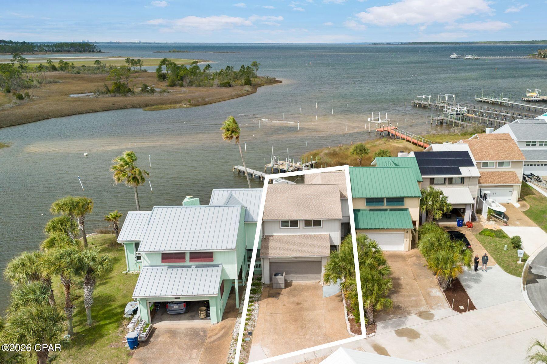 Waterfront living becomes remarkably attainable in this expansive bayfront townhome, where sweeping water views, an impressive private dock and a rare no-HOA setting create an opportunity seldom found at this price point. Soaring cathedral ceilings elevate the formal great room, where an electric fireplace adds warmth and architectural character beneath the dramatic second-story vault. Natural light pours through etched leaded glass accents and the rear wall of windows, drawing the eye toward the bay and the ever-changing colors of the evening sky. The kitchen features elegant Italian porcelain tile and comes fully equipped with all appliances, offering both beauty and everyday functionality. Just beyond the main living area, a glass-enclosed Florida room transitions to a screened sunroom and a generous 26-by-16-foot deck--an ideal sequence of spaces for entertaining, unwinding or simply enjoying the rhythm of the water. Outside, an impressive 85-foot private dock extends into the bay, creating the perfect setting for paddleboarding at sunrise, kayaking along the shoreline, casting a fishing line or relaxing as boats drift by and the sun slips below the horizon. The residence includes three bedrooms, two-and-a-half baths and a two-car garage, along with a charming screened front porch connected by a café-style walkway lined with lighting and flowers. Located within a walkable waterfront community, this property offers the rare combination of space, character and true bayfront living. Panama City continues to grow as one of the Emerald Coast's most appealing waterfront destinations, offering a balance of laid-back coastal living and everyday convenience. Residents enjoy easy access to marinas, waterfront dining, parks and the sugar-white beaches just across the bay, all while maintaining the relaxed pace that makes this area so special.