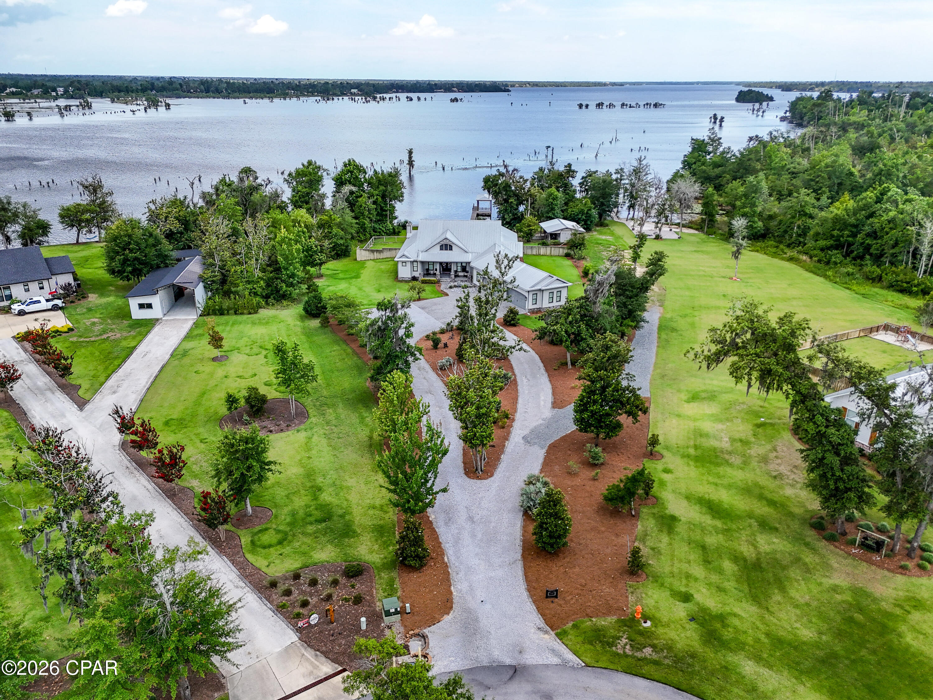LUXURY LAKEFRONT ESTATE IN GATED CEDAR CREEK COMMUNITY -
Experience exceptional lakefront living in this stunning Arthur Rutenberg custom-built home, perfectly situated on 1.9 private acres within the prestigious gated Cedar Creek community. Designed with both elegance and comfort in mind, this meticulously maintained 3-bedroom, 4-bath residence offers breathtaking water views, premium finishes, and resort-style outdoor amenities.

Inside, you'll find soaring tray ceilings, extensive crown molding, and ceramic tile flooring throughout. Large energy-efficient windows fill the home with natural light while providing unobstructed panoramic views of the lake from nearly every room.

The gourmet kitchen is a chef's dream, featuring a spacious center island, double ovens, gas cooktop, Sub-Zero refrigerator, oversized pantry, and an abundance of custom cabinetry. Whether entertaining guests or preparing family meals, this thoughtfully designed space offers both beauty and functionality.  A rare and desirable feature, this home could easily be described as having three master suites, as each bedroom includes its own private bathroom. All three en-suite baths feature luxurious zero-entry tiled showers, creating a spa-like experience for family and guests alike.

The expansive covered lanai serves as an outdoor living room, complete with a fireplace, television, and ample space for relaxing, entertaining, or simply enjoying spectacular lake views year-round.

Car enthusiasts and hobbyists will appreciate the oversized garage with room for up to four vehicles. A large circular driveway and substantial stone-paver parking pad provide additional convenience and impressive curb appeal.  The beautifully landscaped grounds showcase mature fruit trees, including satsuma, apple, and pear varieties. The fenced backyard is designed for both recreation and functionality, featuring a 24' x 28' workshop/storage building, private boat ramp, dock, and covered boathouse equipped with a boat lift--offering direct access to the lake for fishing, boating, and watersports.

This extraordinary property combines luxury craftsmanship, privacy, and waterfront living in one exceptional offering. Don't miss the opportunity to own one of Cedar Creek's most impressive lakefront estates.