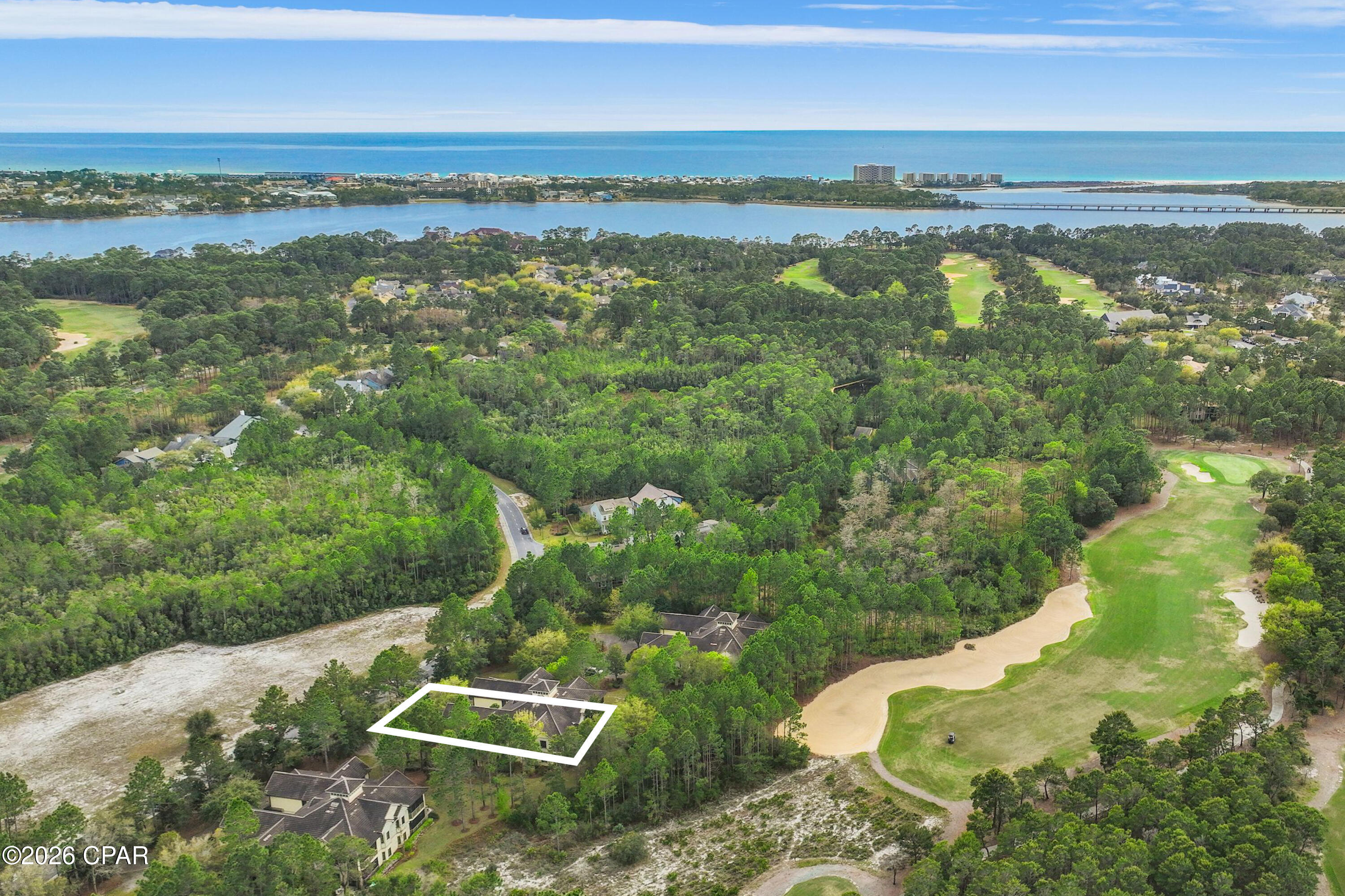 Perched at the top of Clubside II, this rare end-unit residence offers a sense of quiet elevation -- where expansive interiors, filtered golf course views, and surrounding foliage create a setting that feels both private and effortlessly connected to the landscape. Positioned along the ninth tee of Greg Norman's celebrated Shark's Tooth Golf Course, the home captures a softer side of golf course living, with glimpses of manicured greens framed by natural privacy. Inside, soaring vaulted ceilings stretch beyond 12 feet, amplifying the scale of the open living spaces and allowing natural light to move freely throughout. Wide-plank hardwood floors anchor the main living area, while the kitchen is thoughtfully designed for both daily rhythm and hosting alike, featuring granite countertops, stainless steel appliances, custom cabinetry with integrated pull-out shelving, pantry, and a generous layout that flows seamlessly into the dining area and adjacent flex room, ideal as an office or media space. Telescoping sliding glass doors extend the living area outward to a screened porch, where custom shades and tranquil views create an inviting environment for morning coffee or relaxed evenings. This indoor-outdoor connection enhances the home's livability, offering a peaceful vantage point above it all. The floor plan is designed for comfort and separation, with each bedroom functioning as its own private suite. Two serve as primary retreats, including one with dual closets -- one walk-in -- custom wood shelving, double vanities, a skylit tiled shower, jetted tub, and a private water closet. A second suite, set behind double doors, offers generous proportions with a sitting area, ensuite bath, and walk-in closet. The third bedroom is tucked away with its own private feel, ideal for guests. Additional features include a private elevator servicing the main living level, an oversized two-car garage, and abundant storage throughout. With all primary living spaces on one level, the residence offers the ease and comfort of a single-family home. Offered unfurnished with furnishings negotiable, the property also benefits from a fully paid special assessment for exterior improvements, presenting a compelling opportunity for immediate enjoyment or thoughtful personalization. Residents enjoy access to an exceptional collection of amenities centered around Lake Powell, the largest coastal dune lake in the country. From a lakeside pool and hot tub to a fitness center, fire pit, boathouse, private marina, and miles of walking and biking trails, the lifestyle here is both active and serene. Golf, tennis, and clubhouse access are available through membership, completing a well-rounded coastal experience defined by space, privacy, and ease. Just minutes from 30A, Rosemary and Alys Beach, shopping, dining, and the Gulf's white-sand beaches, this home offers the perfect combination of luxury, privacy, accessibility, and resort-style living.
Buyer to verify all data and dimensions if important.