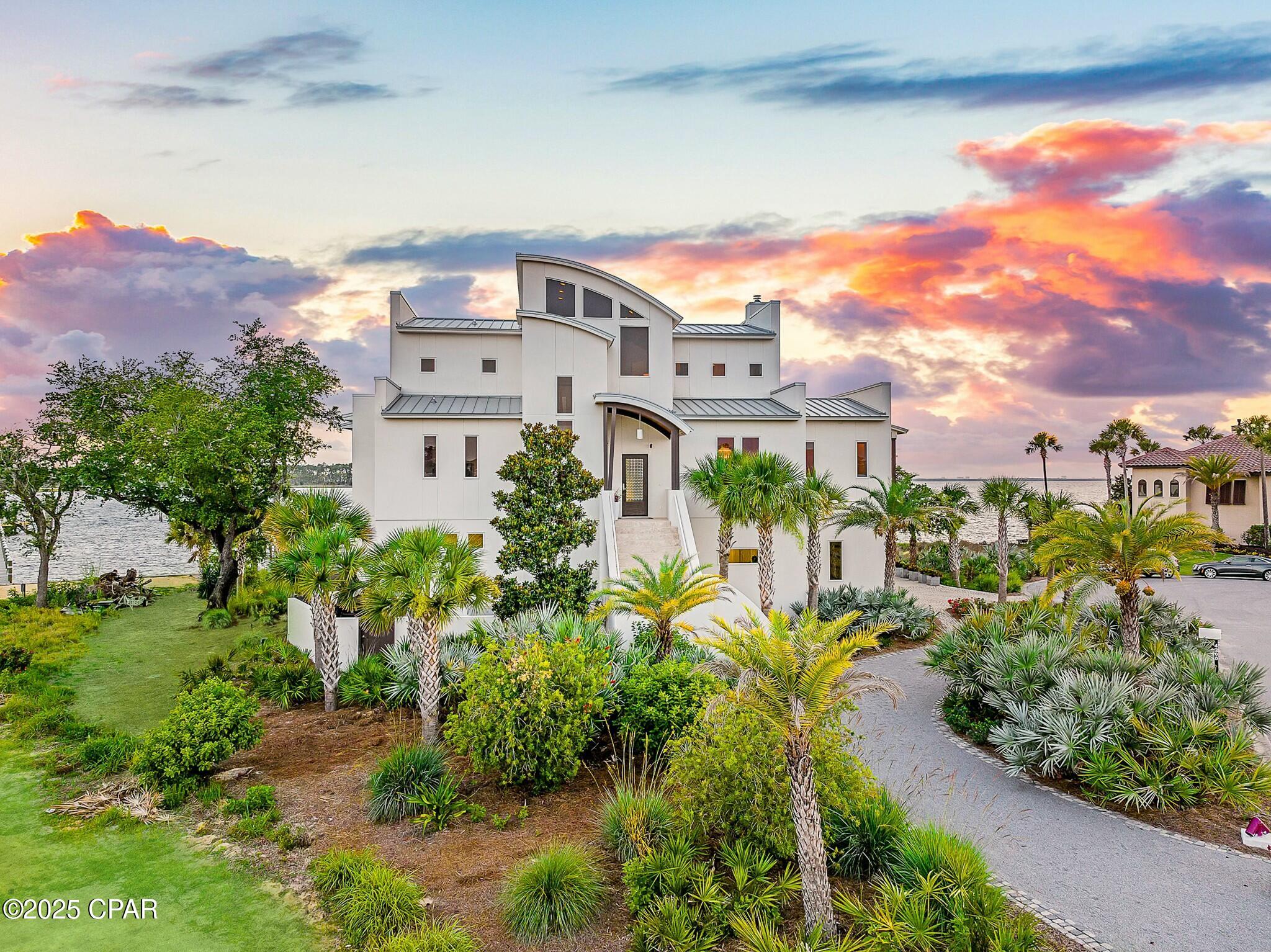 Discover unparalleled luxury on a private island in northwest Florida, where contemporary architecture meets serene tropical beauty. This extraordinary masterpiece was recently featured on HGTV House Hunters Amazing Water Homes in January 2025 and is even more stunning in person than on international TV! 

As you approach Northshore Islands, you're greeted by only a few homes and this home exudes privacy, exclusivity and remarkable architecture. Built by Rita Jones with the design team of Architect Michael Hunnicutt, and Katie Fisher Design, Interior Design, this exceptional three-story contemporary, modern estate spans over 5,000 square feet, offered fully furnished with NEW furnishings and offers breathtaking waterfront views from every room. Enjoy expansive outdoor living with bay-view covered porches on each level, perfect for soaking in the tranquility of the surroundings on the island.

Imagine leaving your dock for Shell Island or heading out for a sunset cruise. Picture yourself with the kids by the pool while watching the sun sink into the horizon. This is one of the very few locations in Panama City, Florida that has been built based on the picturesque views and was designed to maximize views of the water from all angles. This private island is a truly a waterfront dream come true!

For boating and fishing enthusiasts, the property features a private, recently renovated, 350' dock with deep water access to the Gulf of Mexico, which is just 10 nautical miles away with no idle speeds zone in between, offering endless opportunities for fishing and adventure. The dock also holds a 2021 Barletta Pontoon boat on lift and a NEW 40,000 LB boat lift, ALL of which will convey to the new owner to be able to enjoy the waterfront lifestyle from day one! Not looking for boating adventure? This home offers zero entry into the Bay which is perfect for kayaks, paddleboards and swimming as you watch the picturesque sunset set in the West each day. The island's natural landscaping and soothing bay sounds welcome you to this peaceful retreat, where indoor and outdoor spaces blend seamlessly with a saltwater pool and spa.

Upon approach to the circular cobblestone paver driveway, you're greeted by sea breezes and a travertine marble tile entry and a foyer framed with a custom Mahogany wood door with artistic blown glass. Entering the main level, the stunning waterfront views stand out as you sit at 23' elevation and enjoy a great room that offers views of the island from all angles. The family room area is framed by custom millwork and a modern linear fireplace surrounded with marble and slate tile creates warmth in the space while framing a wall of full-glass French doors that lead out onto a covered patio overlooking both pool and Bay. From here you can take in gorgeous year-round sunsets as they sink into the horizon each evening. This level also features a light-filled dining room overlooking the natural landscape of the island and a powder room with Onyx walls and custom pedestal sink for guests, and a junior suite overlooking Bay and pool complete with full bath, walk in closet, and Juliet balcony. Luxurious polished travertine tile is consistent throughout the main floor in the great room for a seamless look.

The open kitchen is fully-equipped and features a custom slab walnut cabinetry, 48'' Thermador Professional convection microwave oven, warming drawer, Viking range hood and full-size Electrolux refrigerator and freezer. A Caesarstone Quartz waterfall countertop island is a showpiece and the oversized island seats 4. The bar and new wine refrigerator are excellent for entertaining and just off the kitchen and adjacent to the 16'x10' walk-in pantry and laundry room with stunning granite countertops, custom cabinetry, washer and dryer and the most perfect views of the island! The primary suite, just off the kitchen, is a haven of luxury, offering radiant heated Italian porcelain tile floors, a spa-like Grohe walk-in shower with 3 body jets and 2 hand showers, new freestanding tub overlooking the Bay, slab walnut cabinetry with Swarovski crystal knobs and direct access to a waterfront patio with a fireplace. This retreat also features a large 14'x9' closet in the primary suite featuring fully enclosed cabinetry. 

The lower level outdoor summer kitchen is an entertainer's dream, overlooking the Bay and pool, is equipped with new luxury appliances, Caesarstone quartz countertops, and custom walnut cabinetry. The pool is framed with luxurious custom tile, Travertine decking and offers new equipment for easy maintenance. With an 18' deep covered patio, your entertaining dreams will become a reality in this world-class outdoor living area. Overlooking the Bay, your boat and the best sunsets that Panama City has to offer - you can't wait to call this one home.

The third level provides a 19"x16" loft living area with remarkable barreled tongue and groove ceiling, waterfront office filled with floor to ceiling glass and doors, and two en suite guest bedrooms, each with walk-in closets and recently renovated luxurious private en suite bathrooms with marble and custom tile finishes.  

The lower level includes a 35"x24" 4-car tandem garage, 15"x10" workshop space, media-game room with full kitchenette, full bathroom and a walk-in wine room, ideal for entertaining being just off the outdoor summer kitchen and pool area. 

The home's robust construction features cement-filled concrete block walls, hurricane-rated Anderson windows, 150-mph wind rated garage doors, safe room and a 1/2" tempered, frameless glass railing system for unobstructed Bay views. A built-in generator fully powers the second and third floors of the home and there are high-efficiency heat pumps for each floor providing comfort and convenience. A solid, standing seam aluminum roof was installed in 2019. The home has a 500-gallon underground propane tank and infrastructure on the island includes high speed internet, city water and sewer. 

This exclusive waterfront home offers a rare opportunity to live the coastal life you've always desired.