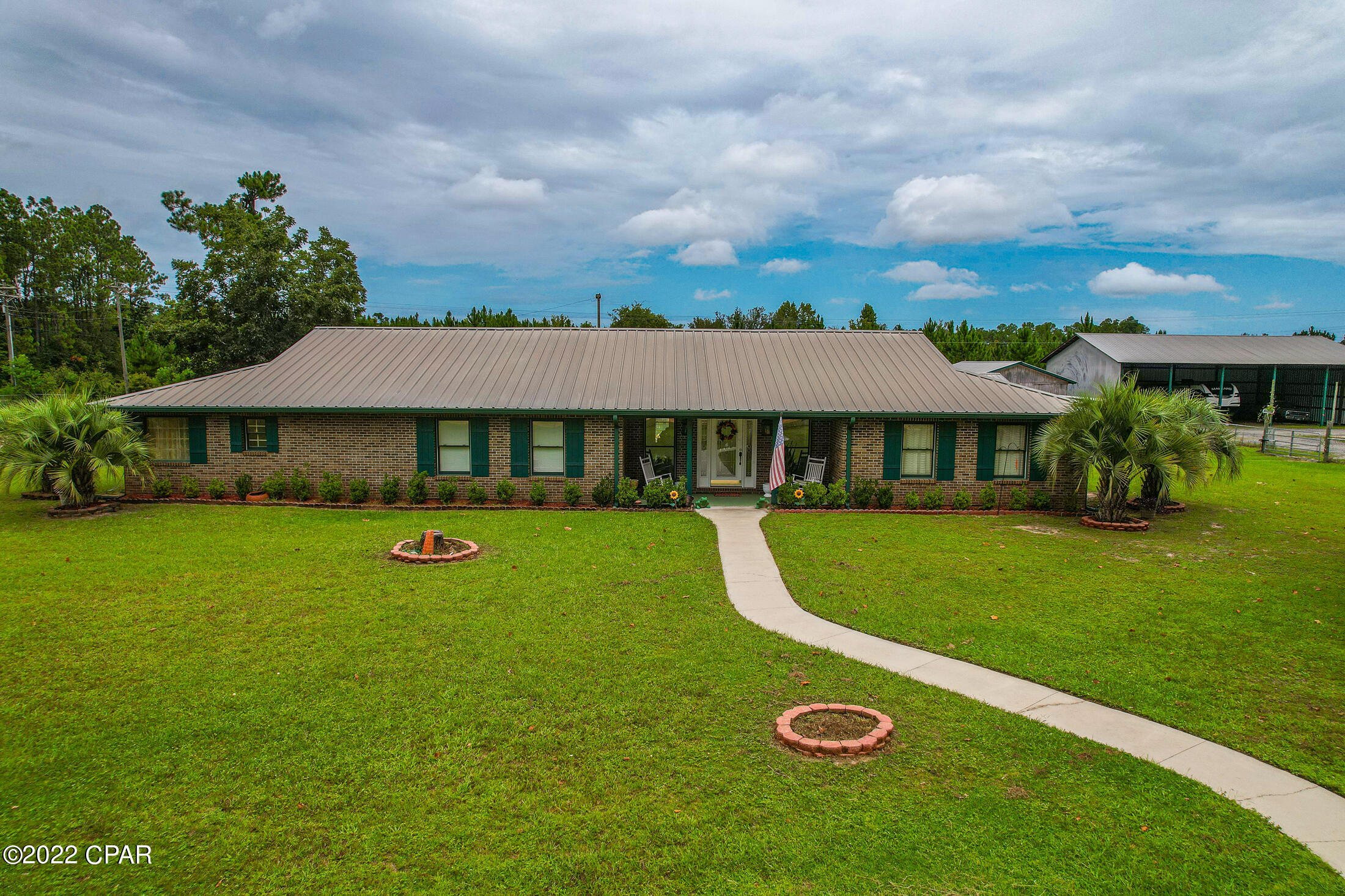 Beautiful and spacious red brick home in a great location on 2.2 acres.  The kitchen is a chef's dream with stainless steel appliances to include a Kenmore Elite refrigerator, stove, separate oven, dishwasher and microwave.  Deluxe kitchen island has a new cooktop and an attached breakfast bar.  The master suite features a huge bedroom with large walk-in closet and a bathroom with garden tub and double vanities. Cozy living room with a fireplace and plenty of room for the whole family. Large laundry room with tile countertops and built-in cabinets.  Home has beautiful hardwood pecan floors, ash floors, and juniper walls throughout.  There is a detached 40x51 metal building, a pole barn, and a 5-stable barn including a tack room. The entire property is 4' chain link fence. The pole barn and metal shop is separated by a chain link cross fence along with an automatic gate.  There are currently 3 renters at the workshop and pole barn - one business renter, one rv, and one boat -and renters do wish to remain, if buyer allows.  Bring your horses and enjoy this country living !!  Only 30 minutes drive to the pristine sugar sand beaches and 15 minutes to the International (ECP) Airport.