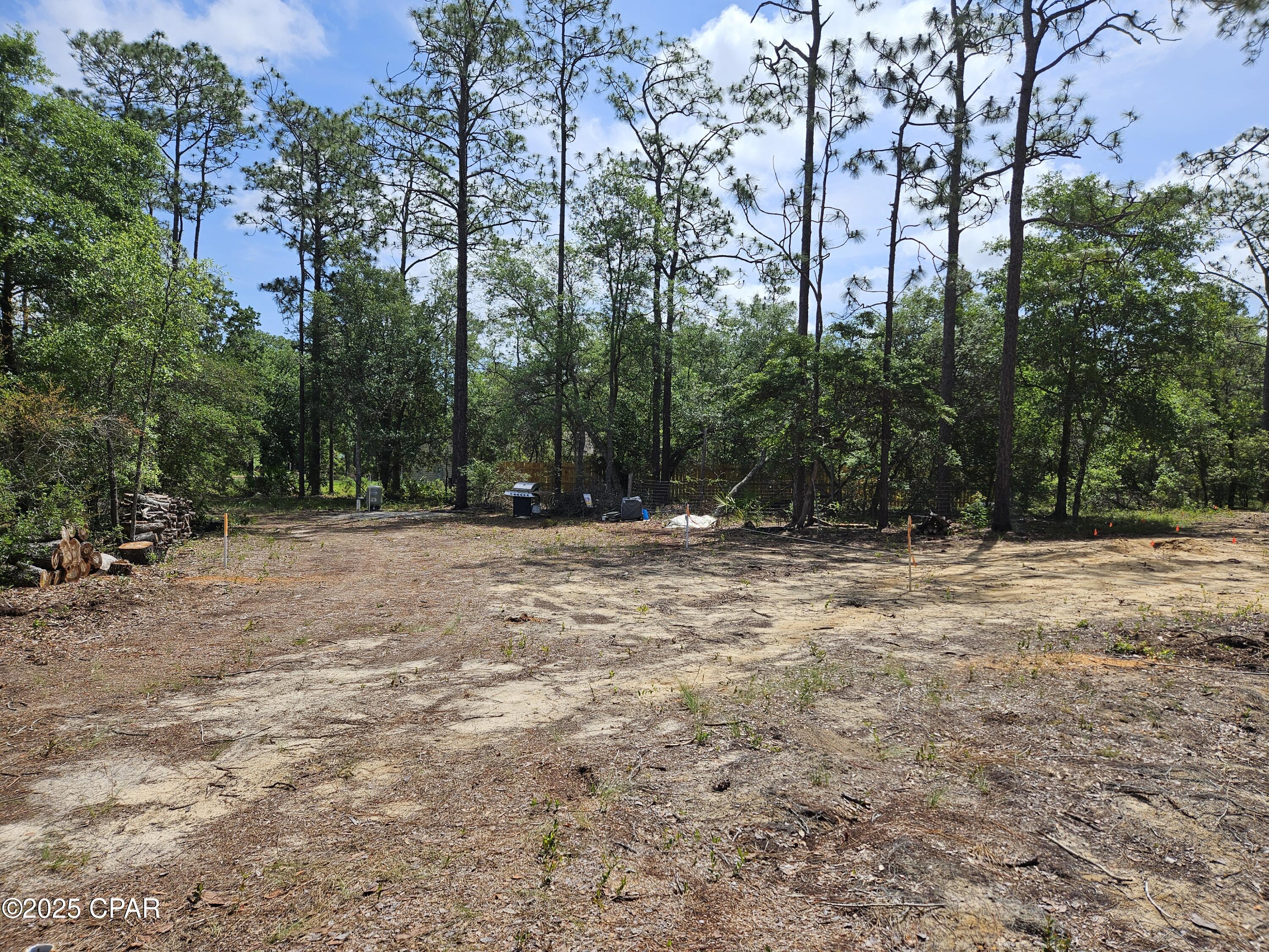 This flat lot has already been prepared for new construction. It has been cleared in the middle, has a deep well, septic tank and field lines, fenced on 3 sides, a circle driveway has been cut, and mailbox is up! It also has a numbered street address and is on the mailbox. A recent survey revealed the lot measures 1.27 acres. Now that Hwy 77 is mostly finished, it does not take long to get the Panama City from the security gated lake subdivision. It's about 30 minute drive to Panama City, and about a 40 minute drive to the World's Most Beautiful Beaches! Live gate guards are on duty weekdays, other times each property owner has a unique code for entry. The resort-like community offers 2 lakes, boat launch, swimming pool, covered pavilion with men's and women's restrooms, basketball court, tennis court, picnic areas, toddler playground and more. The fishing is good and a prime lake for exploring on a kayak or paddle board. Come see how life at the lake can be!