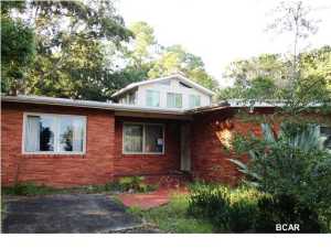 Woodlawn is one of the most established neighborhoods in Panama City Beach. Located right near the Hathaway bridge, it's very convenient to Panama City. This huge, split level home on an oversized lot has great potential. It even has a separate apartment on the second floor with its own outside entrance. This home has lots of big rooms, bonus rooms, a large eat in kitchen and a fireplace in the cozy living room. The yard is irregular in shape but huge. Aside from the carport there is a workshop
