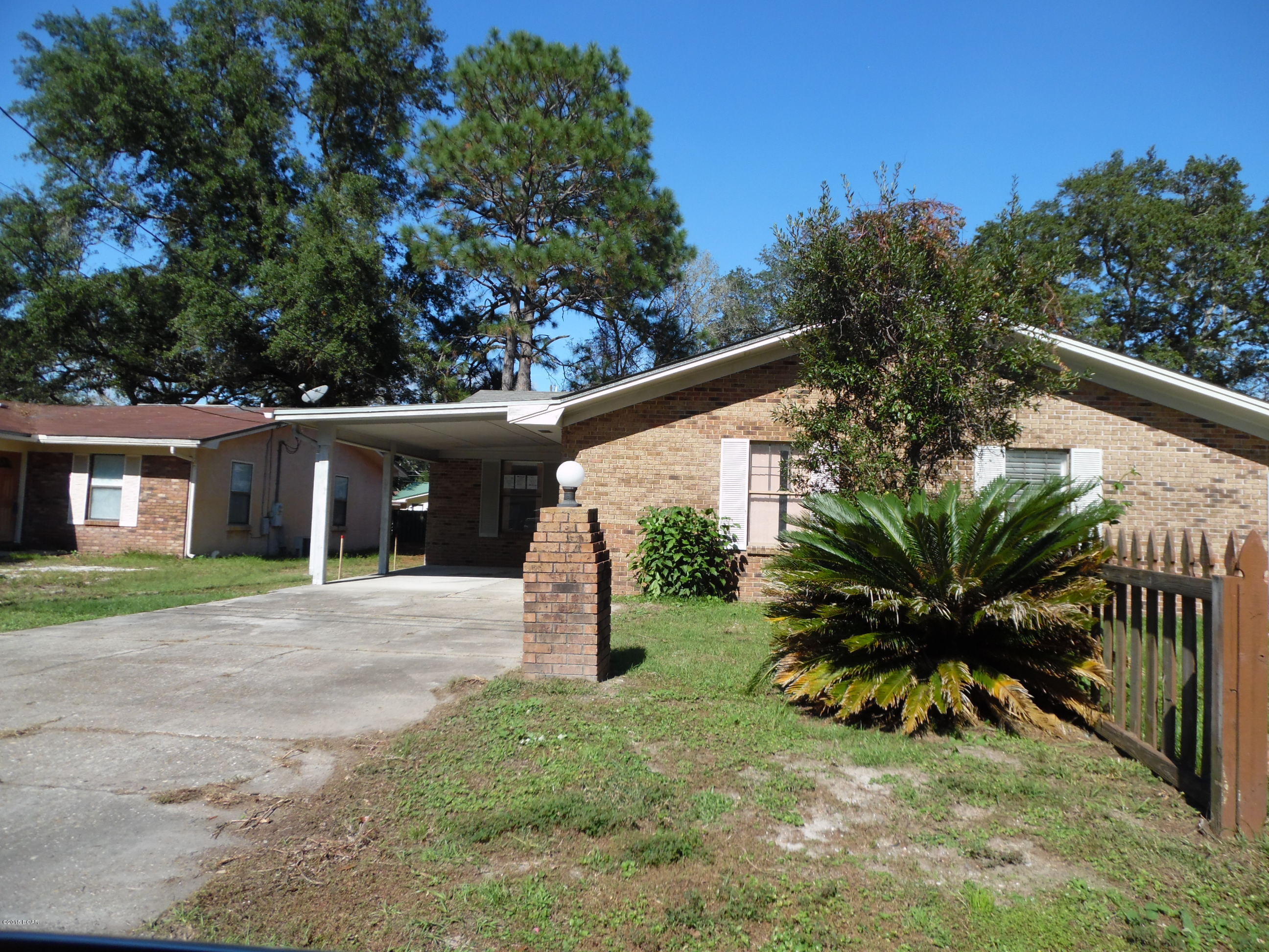 Here's a great opportunity to own a brick home, with a lovely large back yard, covered carport parking and a quiet neighborhood.  This affordable home has a master bedroom with full bath, 2 secondary bedrooms that share a hall bath, a large laundry room and an open-concept floorplan with full visibility of kitchen, dining, living room and sliding glass doors.   There is an outdoor storage room adacent to the large covered patio.  This attached, single family home is super-convenient to Tyndall AFB and schools; and is just 13 minutes from downtown Panama City and local hospitals/doctors.  Best of all, there is no Homeowner's Association or HOA fees.  (All info, dimensions, schools, etc.  is approximate and anything important to buyer should be verified.)