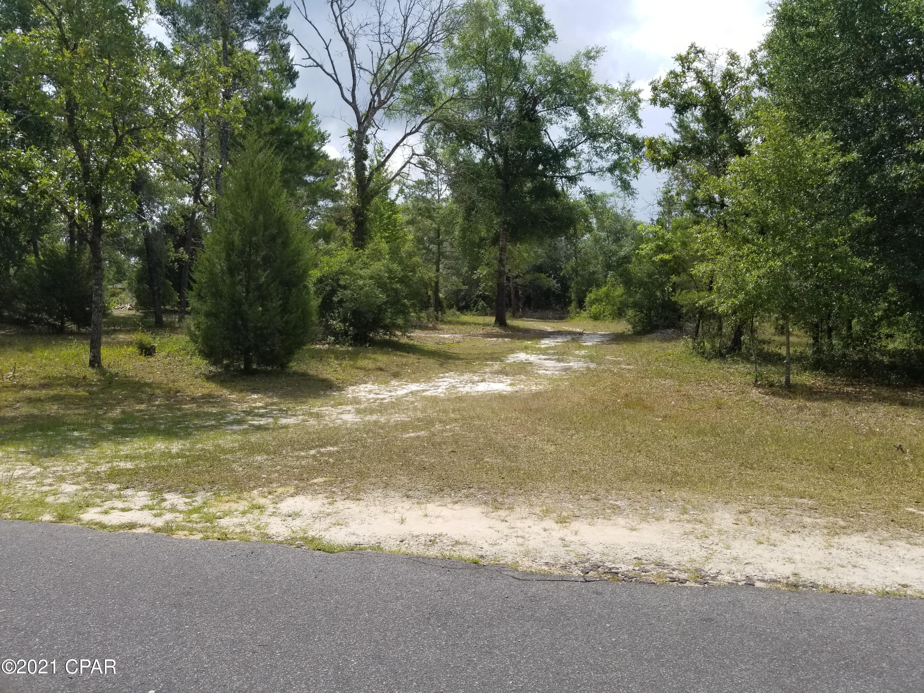 Horses welcome! The huge lot at 5 (+/-) flat acres is one of the largest in the security gated subdivision of Leisure Lakes. Already partially cleared, this flat lot was a former home site so it has a circle drive way, septic tank and field lines. The lot also has a view of the large, clear freshwater lake. The lake is about a mile across, or about 3 miles around. Bring your kayaks or boats and go exploring. In addition, there is a 20x26 steel building with 2 rollup doors, and a 12x24 storage building with an attached 2-car carport. There is plenty of room for horses or trail riding. The property backs up to a wildlife preserve surrounded by a 10-foot tall fence.  Subdivision amenities include basketball court, tennis court, boat launch, fishing, swimming pool, covered pavilion, men's and women's restrooms and more. Only 30 minutes from Panama City, 25 minutes to Chipley, and 45 minutes to the World's Most Beautiful Beaches. Live security guards are on duty weekdays, and each resident has a unique code for entry. In addition, there is a second lake that is about half the size of the big lake and also is spring fed. This would be a great family homestead or bugout property. Be sure and see all of the photos.