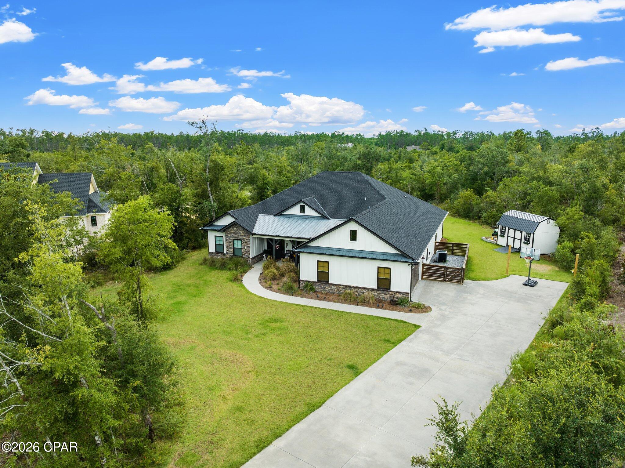 Back on market due to no fault of the sellers. Welcome to this beautifully crafted custom home offering 2,912 square feet of thoughtfully designed living space on a private 1.74-acre lot in a desirable gated community. Built in 2018, this 4-bedroom, 3-bath residence combines modern comfort with timeless style, all just a short drive from Panama City Beach.

Step inside to an open-concept layout featuring 10-foot ceilings, abundant natural light, and high-end finishes throughout. The heart of the home is the spacious kitchen with an oversized 10-foot island, seamlessly flowing into the living and dining areas--perfect for both everyday living and entertaining. A cozy brick fireplace anchors the living room, while LVP flooring runs throughout the main areas for durability and style.

The oversized primary suite offers a private retreat with direct access to the screened-in back porch, creating a seamless indoor-outdoor living experience. The en-suite bath features a walk-in shower with bench and a 6-foot soaking tub, while secondary bathrooms include upgraded 5-foot soaking tubs. Additional spaces include a dedicated office and a fully equipped movie room, providing flexibility for work, relaxation, and entertainment.

Enjoy quiet mornings on the covered front porch, complete with a charming porch swing, or unwind in the spacious 18x10 screened-in back porch overlooking your private, wooded backyard. The outdoor space is truly one of a kind, featuring a custom tree fort and obstacle course tucked into the woods--perfect for adventure and creating lasting memories.

The home's exterior showcases a beautiful blend of stone and board-and-batten siding, enhancing its curb appeal. Located within a gated community offering a pool, clubhouse, playground, and private dock access to Deer Point Lake, residents enjoy both privacy and convenience.

Don't miss your chance to own a unique property that offers space, privacy, and lifestyle all in one.

New roof will be added by end of June.