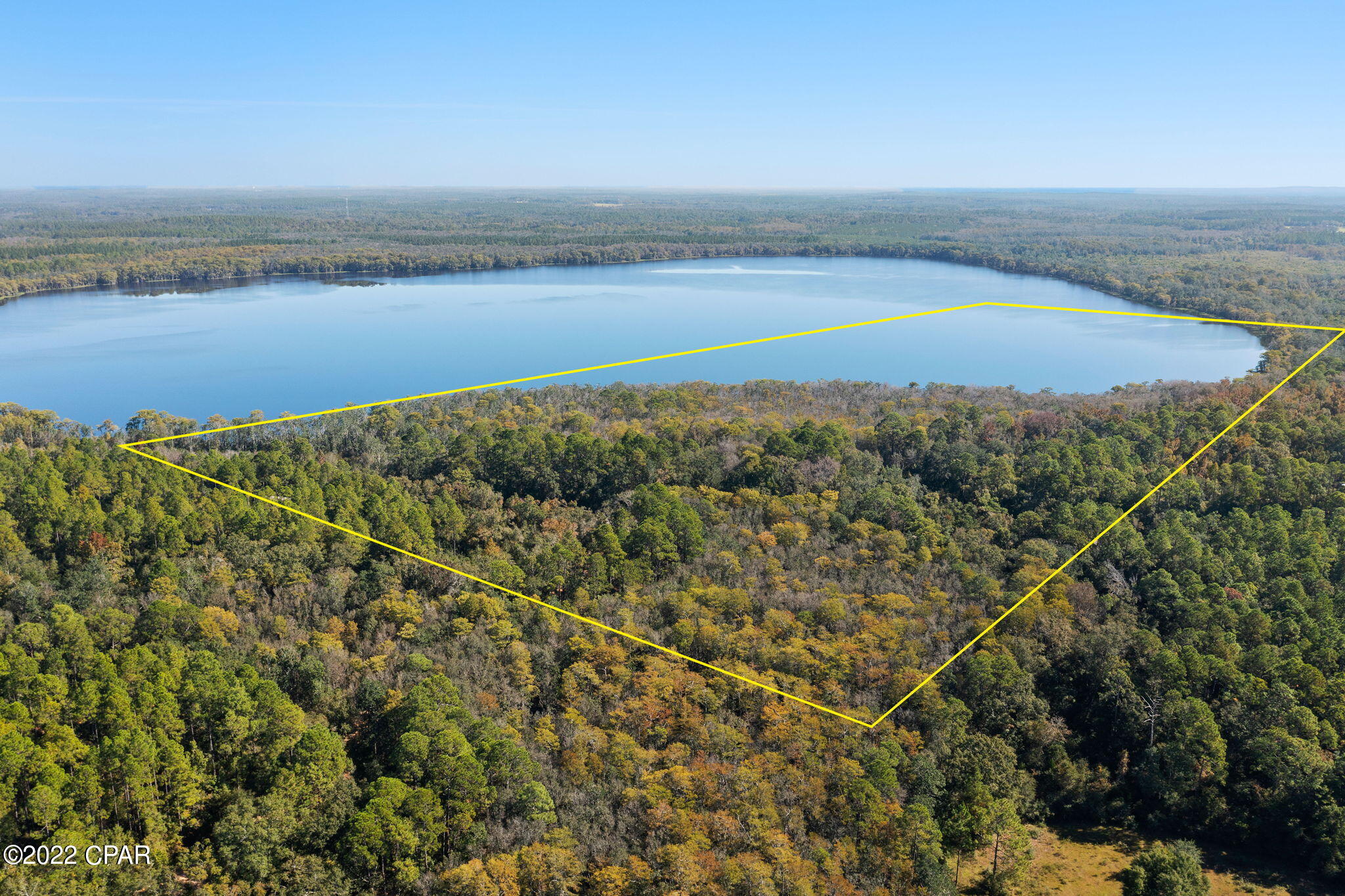 What a wonderful place to relax and wet a line! Perfect for HUNTING, RECREATION, and MORE! This rare parcel is located on a paved road with over 1,000 ft of road frontage and a small portion of land across the street, offering a private yet convenient access. The property also offers approximately 3,350 ft of serene water frontage. Some of the property is already cleared and mulched- ready for a home! Approximately 36+/- acres of the parcel is land and the remainder is lake. The land is absolutely gorgeous, featuring a lush tree canopy with large Live Oaks and Cypress trees. There is already a driveway with a culvert and a gate so you can walk or drive the clearing cut back to a landing on the lake that has been there for years and reach the water's edge with an incredible view. The county public boat landing is right down the street as well. Catch bream, bass, catfish and more! Watch the sun set on the lake from your back yard. This property would be perfect for a picturesque home-site, weekend getaway on a freshwater lake in Florida, or turn it into a waterfront investment. The opportunities with this gorgeous property are endless!  It is also nearby to some of Florida's natural wonders, freshwater springs and creeks. Less than 45 minutes from Panama City Beach, this is the perfect location to escape to nature and be a short drive to emerald waters and sugar sand beaches.

Buyers should do their due diligence with the appropriate county/state/environmental departments to verify usability since there are wetlands and conservation zoning located on the property. It is undetermined by the sellers how much and what the land can be used for currently. All sizes/info approximate and based on county records. No survey or environmental studies have been done nor are available- buyer to obtain if important.