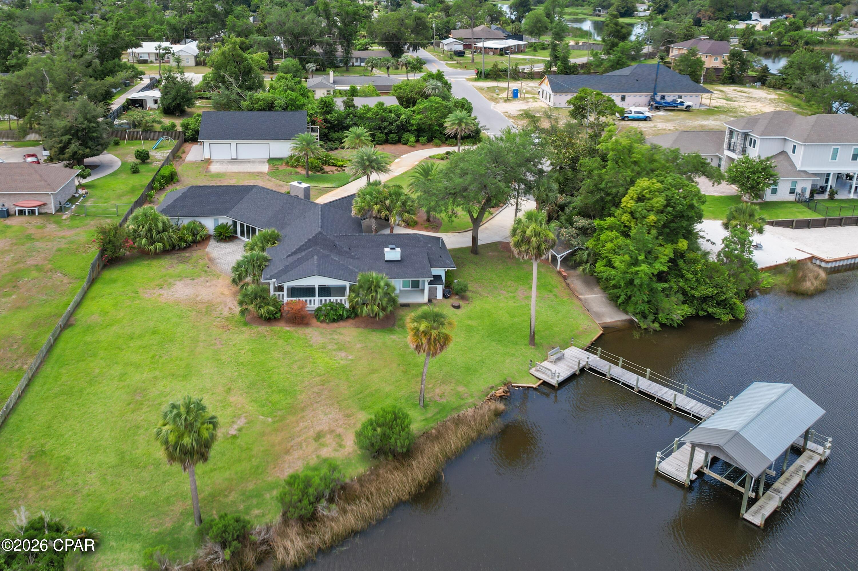 LYNN HAVEN WATERFRONT LIVING WITH AN INCREDIBLE GARAGE! Situated on scenic Anderson Bayou, this thoughtfully designed 3-bedroom + bunk room home offers panoramic water views and exceptional indoor and outdoor living. Nestled on a beautifully landscaped lot with mature trees and a circle driveway, this property provides easy boat access to North Bay and is just a golf cart ride from the Panama Country Club.  Designed for both everyday living and entertaining, the spacious interior features an inviting open living area with vaulted ceiling, a gas fireplace, and a dining room complete with a wet bar. (Great for Entertaining) The chef's kitchen boasts a large island with breakfast bar seating, stainless steel appliances, a walk-in pantry, and an additional butler's pantry/utility room. Just off the kitchen and overlooking the bayou, there is a covered back porch AND a large paver patio, creating the perfect settings for relaxing or entertaining guests.  The waterfront master suite is a private retreat featuring a gas fireplace with room to sit around it, direct access to the backyard, a walk-in closet, and breathtaking bayou views. The additional bedrooms are generously sized and offer ample closet space.  Outdoor amenities include a covered boat lift, dock, and access to a small boat launch. The oversized 46x30 detached garage is truly a showpiece, featuring high-end trim work, a kitchen area, air compressor hookups, specialty lighting, and a climate-controlled upstairs room ideal for storage, a home office, gym, or game room.  Additional highlights include a carport with built-in column storage, dual HVAC systems, security system, sprinkler system on a well, landscape lighting, a newer roof, and a desirable dead-end street location near the Panama Country Club and Lynn Haven boat launch. This exceptional waterfront property offers the best of the Florida lifestyle. Call today to schedule your private showing.