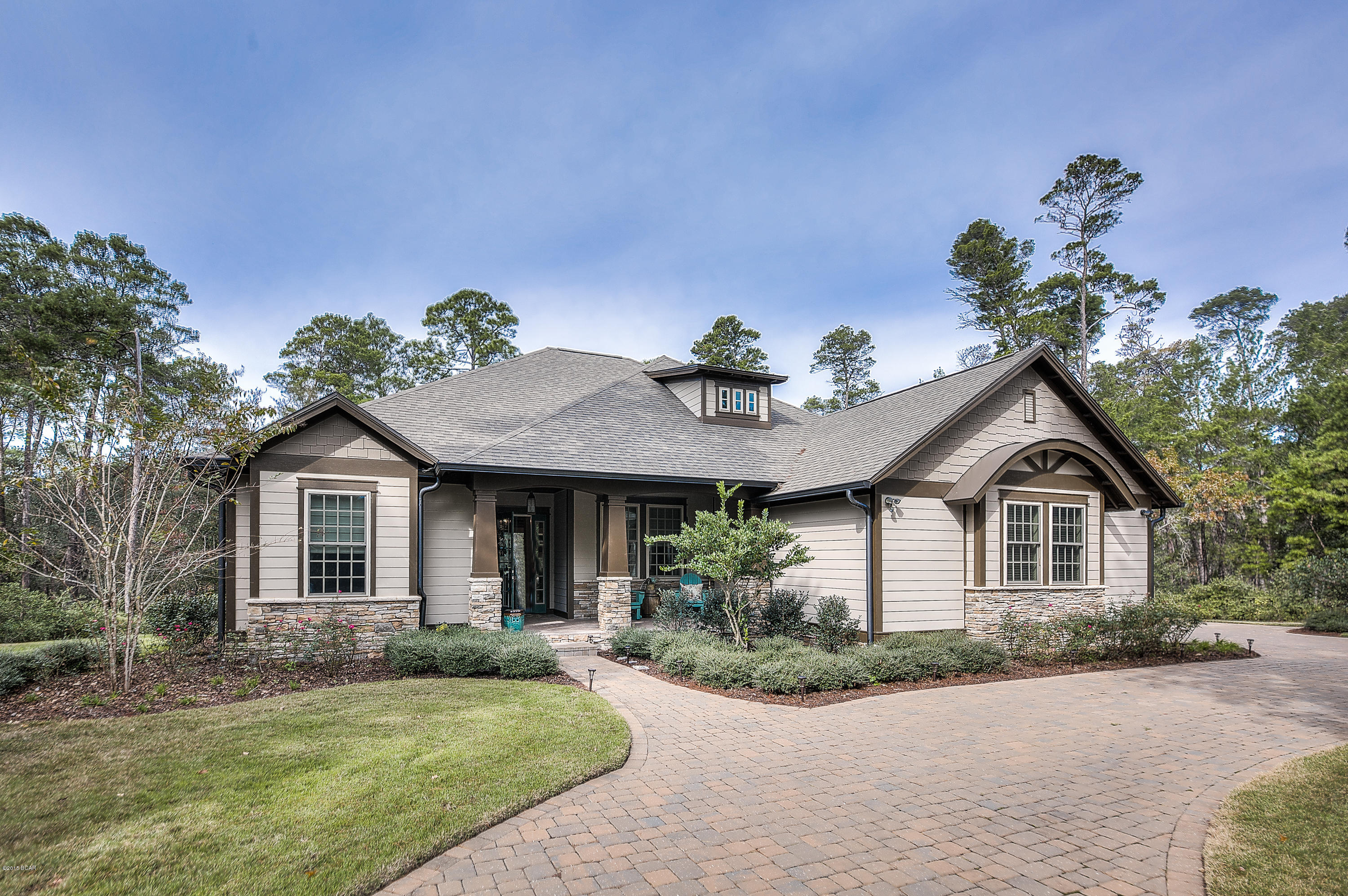 Beautiful craftsman style single level home on .829 acres in Wild Heron! This home welcomes you with a beautiful brick paver circle driveway and river rock column front porch. The open floor plan and high ceilings make home perfect for entertaining. It also features both a formal and casual dining area. The large kitchen island opens to the living area that features a fireplace and doors that are completed with electronic blinds. These doors open to a large screened in porch. They can open completely so it is as if these two areas are one, or remain closed to make 2 completely separate areas, you choose! The large screened in porch is complete with several sitting areas, a summer kitchen, fireplace and media area. There is also an open deck area perfect for grilling. The deck and porch overlook a peaceful wooded area. The home has 3 bedrooms and 3 bathrooms. The master bedroom, bath and walk in closet are on one side of the home and the two additional bedrooms are on the other side. There is also a wine media room that features wine racks, desk space, TV and a sitting area. Throughout the entire home is a $10,000. built in Nuvo sound system that is connected to the internet, to allow you to connect to subscriptions such as Pandora. The home has a spacious 3 car garage with a finished area above providing more than ample storage. All this and the home is on a dead end cul-de-sac road! If you are looking for peaceful living just minutes away from the beach you have found your home. This is a must see, call to schedule a showing today!