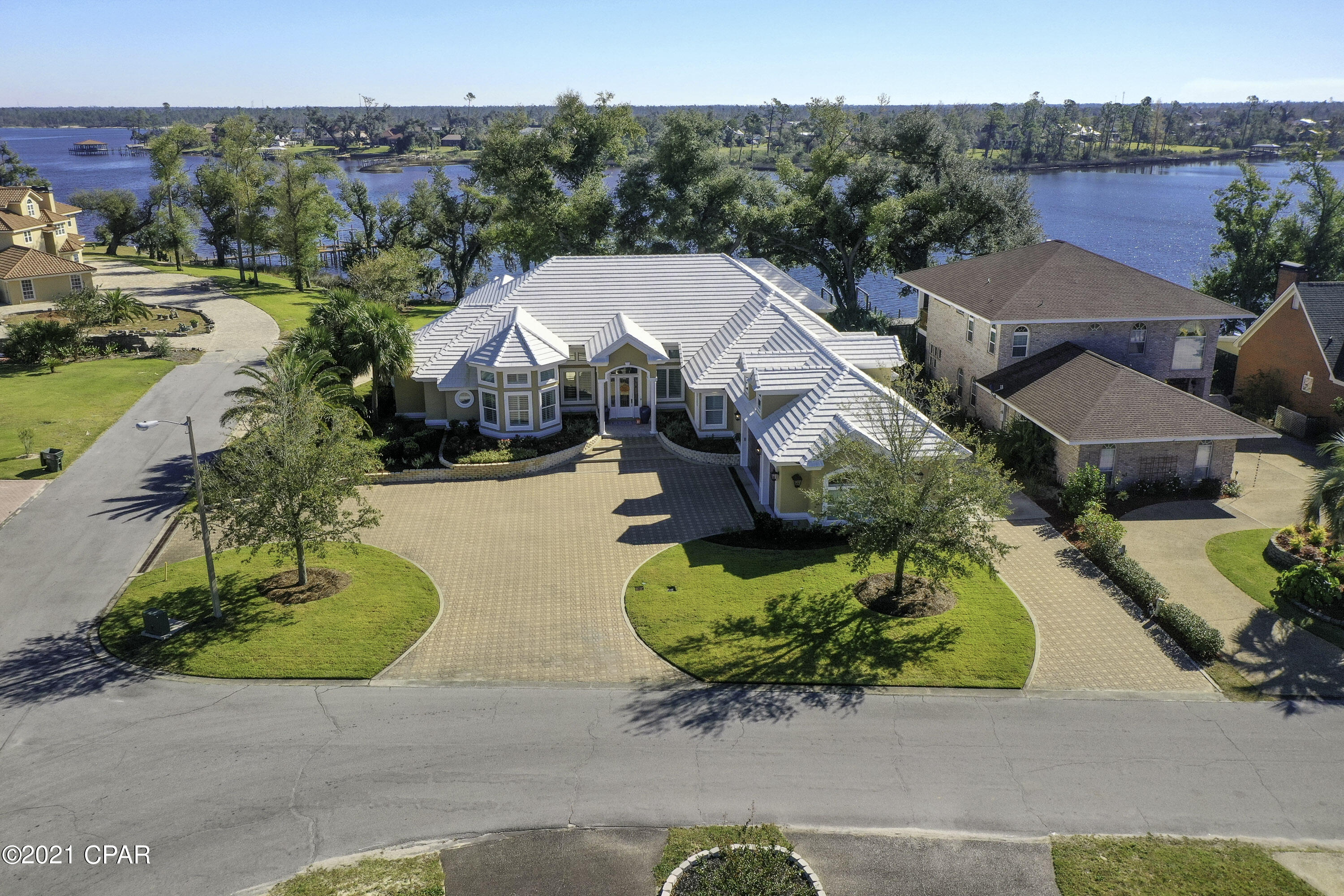 Exquisite waterfront estate in the Panama Country Club in Lynn Haven. The interior of this home features hard wood floors, plantation shutters throughout, filled concrete block construction with stucco overlay & some of the best waterfront in Lynn Haven. The grand entrance opens up to a formal living/dining space with fireplace & built-ins overlooking the brick paver back patio through 3 sets of French doors. The master suite includes floor-ceiling mirrors in the dressing area, double sink vanity with soft close hinges, large tile shower, & makeup vanity. Inside the master bedroom you will find his/hers walk-in closets, tray ceiling with ambient lighting, sitting area with built-in bookshelves, and sliding glass doors overlooking the water & patio. The kitchen includes a surplus of