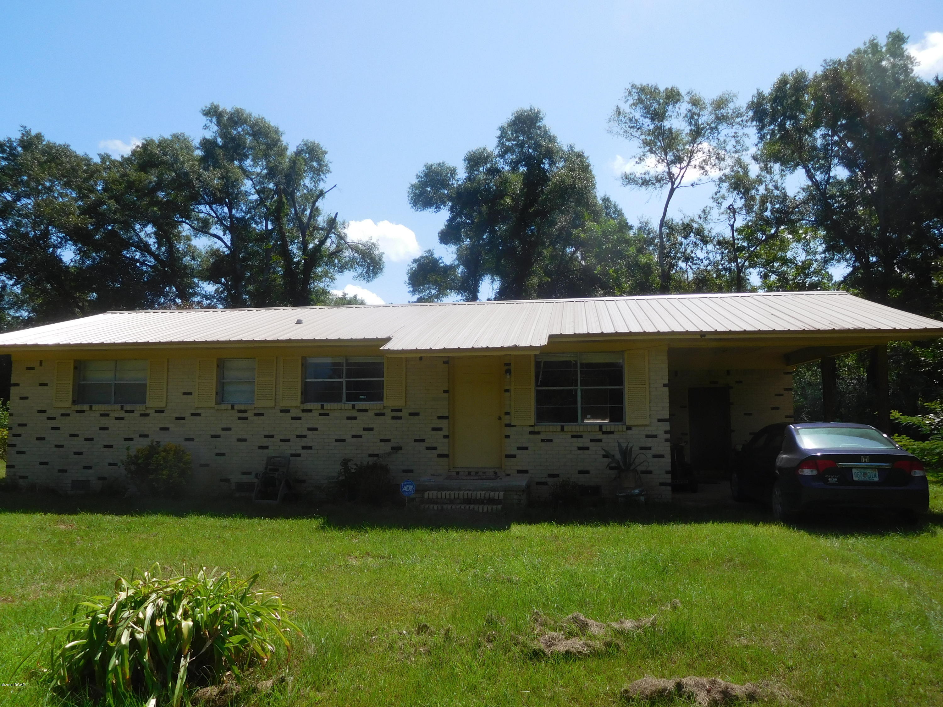 Nice three bedroom one and half bath home on 5 acres. This Brick  Ranch home sits high on a hill. Homes has hardwood floors through out,and newer appliances. Newer metal roof.  Beautiful yard and fields.Older pole barn and yard Building. Have your small farm or peaceful retirement home in a very popular area. Close to beaches and Panama City.Nice private location .