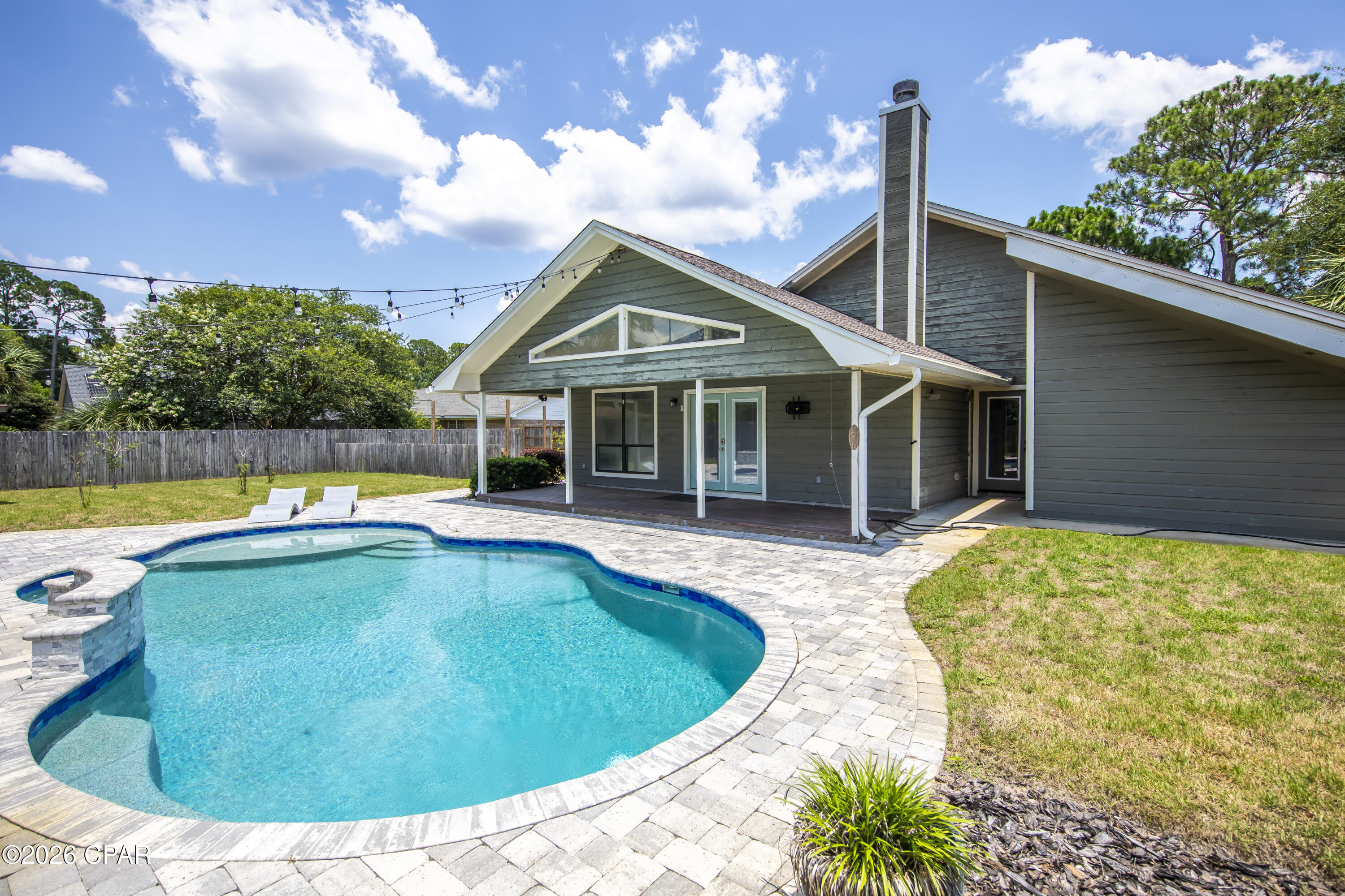 Welcome to this beautifully updated home in the highly sought-after Colony Club Community, home to the renowned Legacy Golf Course. Offering 3 bedrooms, 3 bathrooms, and a versatile flex room., this spacious residence  combines comfort, style, and functionality just minutes from the white sandy beaches, Pier Park, shopping dining, and entertainment. Step through the foyer to see the unique interior/ outdoor solarium, perfect for morning coffee, reading or your own private garden retreat. The open concept floor plan seamlessly connects the living, dining, and kitchen areas, making it ideal for everyday living and entertaining.The living room features soaring tongue-and-groove vaulted ceilings, custom trim, and a cozy wood-burning fireplace that creates a warm yet elegant atmosphere. The spacious primary suite offers room for a sitting area, large a large walk-in closet, and a beautifully renovated ensuite bath featuring a tiled shower, double vanities with make-up mirrors, and a private water closet. Two additional bedrooms bedrooms with thier own full bathrooms, while the flex room provides as a 4th bedroom, home office, gym or hobby room. Step outside to your own private backyard oasis featuring a large covered porch, a heated chlorine pool with expansive lounging area, and a premiun Hot Springs  saltwater hot tub valued at approximately $22,000.00-the perfect place to unwind after a day at the beach. Energy efficient solar panels help keep the electric cost to a minimum. Recent improvements include new plumbing throughout the home, a new sewer line to the street, new Zoysia sod with irrigation in the front and backyards, fresh interior paint, new sky lights, new refrigerator, microwave, double ovens, UV filtration systems added to both HVAC units, updated lighting, some new blinds, smoke alarms, and a new pool heater. Conveniently located with easy access to Highway 79, Panama City Beach Parkway, and the Gulf, you'll also enjoy having The Legacy Golf Course and a Gayle's Trails entry in your own neighborhood! Pier Park is also less than 4 miles away! This move-in-ready home offers the perfect blend of luxury, convenience, and coast living.