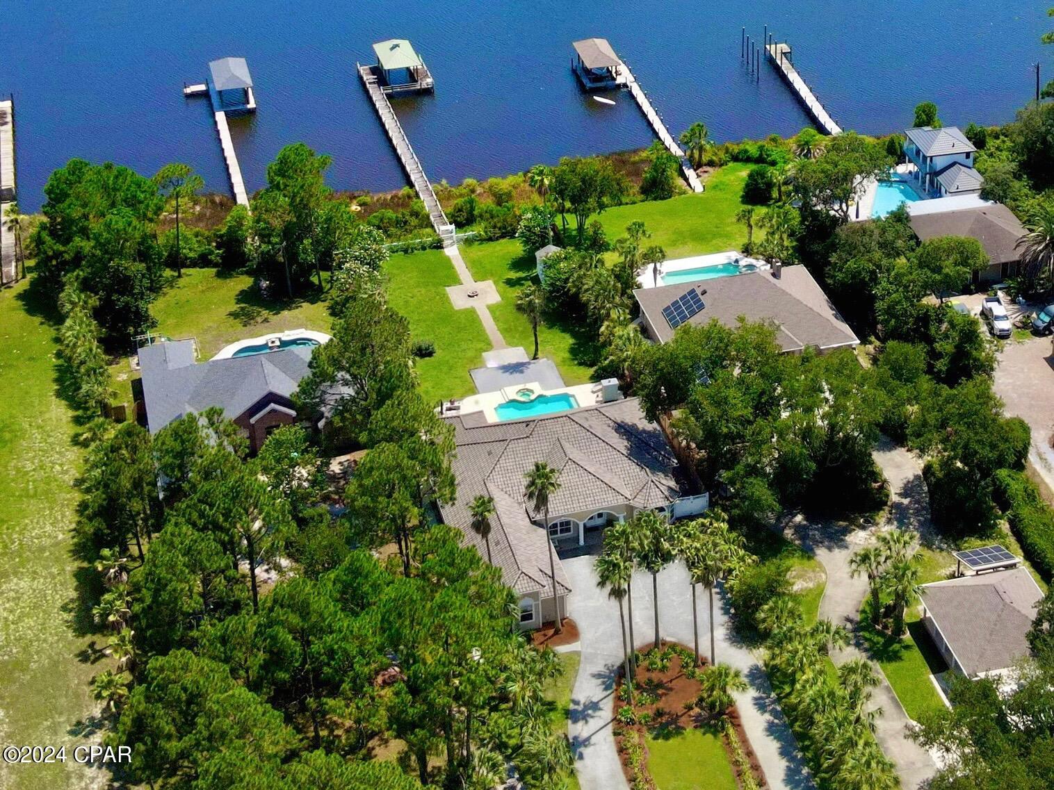 CURRENTLY UNDER CONTRACT, SELLER WILL CONSIDER BACKUP OFFERS. This luxurious WATERFRONT property has it all! Located in the heart of Panama City Beach, this gorgeous 4 bed/3.5 bath home offers an open concept with high ceilings, oversized 3 car garage, all the updates, deep water gulf access for boats, jet skis, kayaks & paddle boards. Hookups for RV, a heated pool & spa, tropical landscaping, privacy & a 90' stretch of deep blue water frontage leading to the gulf! Imagine hopping on your boat whenever you'd like, to head out for a few hours of fishing, maybe a day trip to a nearby island or restaurant, or further out into the Bay or Gulf for snorkeling or scuba diving. When you aren't enjoying water activities, you have almost an acre of land for other hobbies. There is plenty of space for a vegetable garden, keeping chickens for fresh eggs, or practicing your favorite sport. There is even room to add a coach home on the front or back of the property if you so desire. 

Imagine coming home to this prestigious property, pulling in through the double columns, and up the majestic 500 foot circle drive, lined with lush green palm trees. Then inside, this home showcases formal & informal living & dining areas, all in keeping with an open floor plan. It is the perfect layout with 2 bedrooms & bathrooms located on one side of the house, the master suite & 4th bedroom/office on the opposite side of the home, and it is all on one level! The spacious interior boasts 10-12ft ceilings, 2 gas fireplaces, kitchen island with second sink, bar to seat 4+, breakfast nook with bay window, reading nook overlooking the pool area & so much more! The enormous master accommodates the largest of bedroom furniture, has two separate sitting areas, two walk-in closets, gas fireplace, and French doors leading right out to the covered patio and pool areas. The newly renovated en suite bath consists of double vanities, custom walk-in shower, and separate whirlpool tub.

Being at the beach is a wonderful opportunity to enjoy the outdoors. 7903 North Lagoon Drive offers the optimal setting & space for you to thoroughly enjoy outdoor living! Head out on your boat, or enjoy your own backyard poolside. To enhance your outdoor experience, you will find a covered outdoor kitchen with refrigerator, gas stove, sink, automatic shutters, and a bar to seat 4-6 people. The updated, heated pool & spa with custom pool lights can be controlled remotely, and is all surrounded by an enormous open deck, which connects to the large covered patio, and can be accessed by all the main rooms via double French doors. Even more special qualities includes a 160' boat dock, 12'x24' boathouse & custom shed. This home sits high in flood zone X, so no flood insurance required, and no HOA. That means if you prefer to rent your home on occasion, you have the freedom to do so. This house has been completed updated! You will find a new tile roof, new storm windows & doors, whole lawn irrigation system, renovated baths, tankless water heater, gorgeous new kitchen countertops, sinks, & upgraded stainless appliances, including a double oven & wine refrigerator, plantation shutters, a whole house security system & a huge garage equipped with a Tesla charger plus one additional EV charger. 

Located along the deep waters of Grand Lagoon, you are only minutes from the Gulf of Mexico, St. Andrews State Park, Shell Island, local restaurants & entertainment, concerts, wine & food festivals, farmers market, golf courses, sport fishing and more! So bring your boats, your bikes & yourself to make this property your own perfect paradise today! Information is approximate & should be verified by buyer if important.