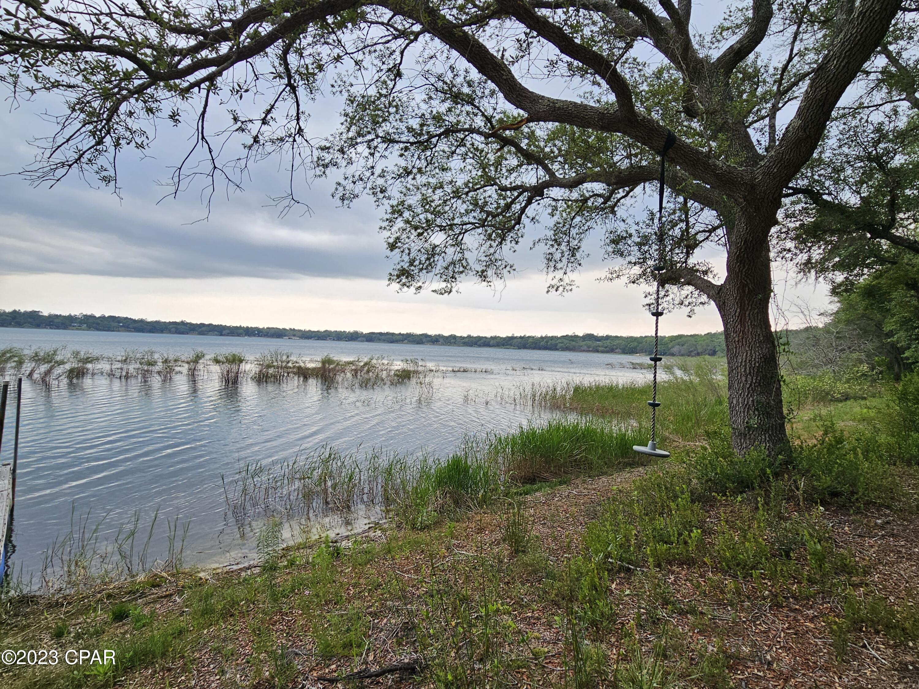 CURRENTLY UNDER CONTRACT, SELLER WILL CONSIDER BACKUP OFFERS  This waterfront lot on the big lake in Leisure Lakes is begging for a new home with a lot of glass on the water side to take advantage of the amazing sunsets. This is a rare opportunity to own a piece of paradise on the east side of the lake to be amazed at the sunsets over the water. It is one of the clearest and cleanest lakes in Northwest Florida. It is good for swimming, fishing, kayaking, snorkeling and just laying on a float and drift away. The lake is about a mile across, or about 3 miles around. It has already been cleared and has a 20x30 pole barn with a concrete floor. Backing up to it is a 12x24 metal storage building. The security gated subdivision offers amenities such as a basketball court, tennis court, toddler playground under oak shade trees, grill stations, picnic tables, pool, and a concrete boat launch with a gentle slope. Live gate guards are on duty weekdays, and residents have access with a private code.
