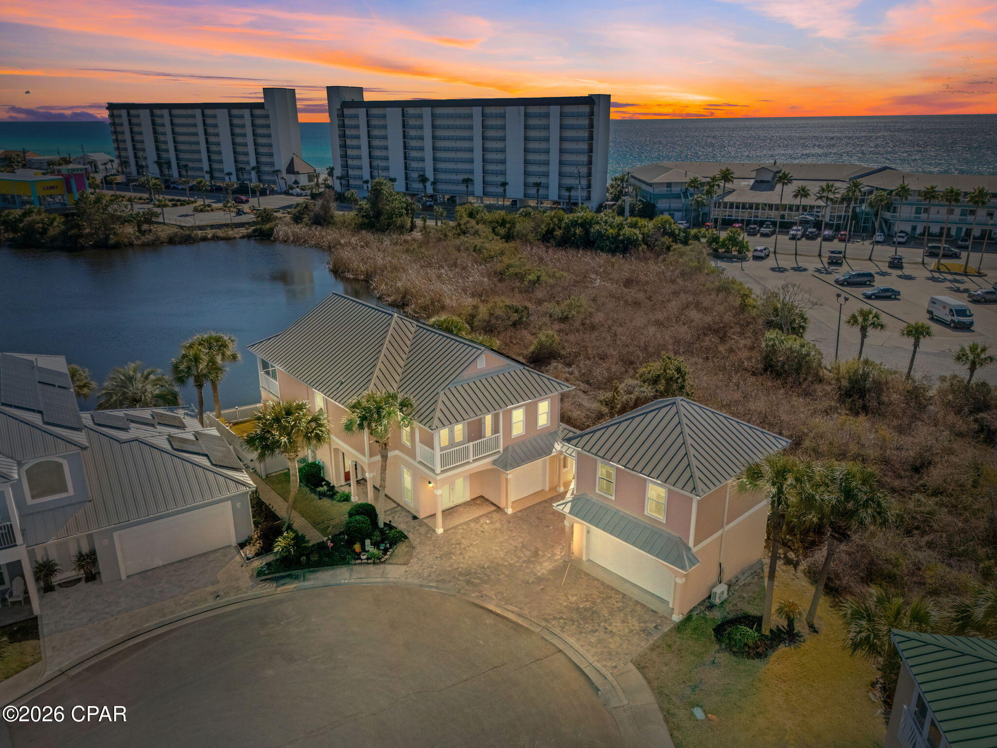Tucked into the highly sought after west end subdivision of Lakes at Summer Breeze, this custom built home with an attached carriage house is the kind of property buyers wait for and rarely find. Enjoy lake and Gulf views, sunsets from multiple balconies, and a short walk to Beach Access 66. The 2,888 SF main home offers 4 bedrooms, 3 full baths, high ceilings, walls of windows, plantation shutters, tile and wood floors, a gas fireplace, and an updated kitchen with custom cabinetry and gas stove. The first floor suite has its own entrance and is perfect for guests. Upstairs, the oversized primary suite feels like a retreat, complete with a seating area or office, hardwood floors, nice bath room with a soaker tub and shower, and a full width screened balcony overlooking the lake that will absolutely become your favorite sunset spot. Two additional spacious bedrooms one with built in bunks, a wet bar, shared balcony, and full bath round out the second level. The carriage house adds serious value a 2 car garage plus a 441 SF studio apartment with full kitchen, full bath, and tankless water heater ideal for guests or multigenerational living. Outside, enjoy paver patios, an outdoor shower, and daily wildlife sightings such as turtles, ducks, osprey, and even eagles. Bonus perk? Solar panels will be paid off at closing, keeping monthly electric bills refreshingly low. This is PCB luxury living done right.
