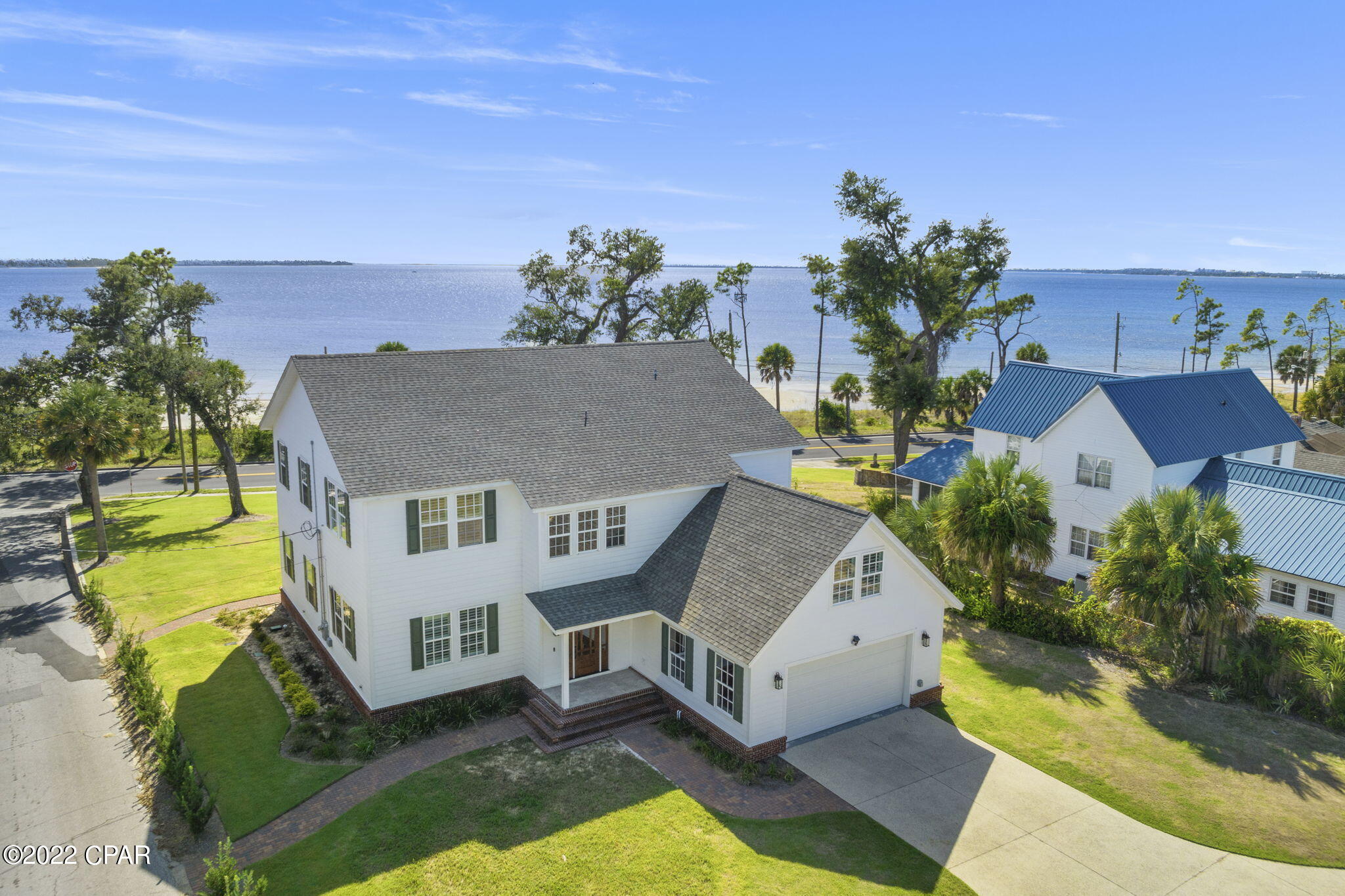BIG BAY VIEWS. BIG BEACH DRIVE PRESENCE. AN ADDRESS PEOPLE KNOW. Positioned across from St. Andrews Bay in Panama City, Florida, 900 W Beach Drive brings Coastal New England-inspired character to a home designed for life on a larger scale. The big-picture appeal begins with a half-acre corner lot adjoining an alley, creating an even bigger sense of openness and separation along one of Panama City's most recognizable residential corridors. A huge screened patio frames panoramic views across St. Andrews Bay, while impact-rated windows carry those views into nearly every room. Inside, the scale reaches its peak with approximately 4,372 square feet and massive living spaces spread across two levels. Hardwood flooring continues through four upstairs bedrooms, two additional flex rooms, an office, an upstairs loft and living area, the main living space, and the kitchen. Two living areas, four full bathrooms, and multiple private flex spaces provide substantial room to live, work, host, and adapt. At the center of it all, the well-appointed kitchen features stainless steel appliances, granite countertops, an island, and bar seating. Beyond the biggest spaces, the smaller details matter just as much: ten-foot ceilings, crown molding, wireless motorized window treatments, extensive built-in storage, granite countertops in all four bathrooms, and three laundry connections, including one in the upstairs primary bathroom. Designer furniture is negotiable. From its broad bay views and generous proportions to its unmistakable position on West Beach Drive, this is a substantial residence with a presence that extends well beyond its walls. Downtown Panama City, local dining, shops, marinas, boatable waters, and the shoreline of St. Andrews Bay are all conveniently accessible. All information is deemed reliable but not guaranteed; buyer to verify if important.