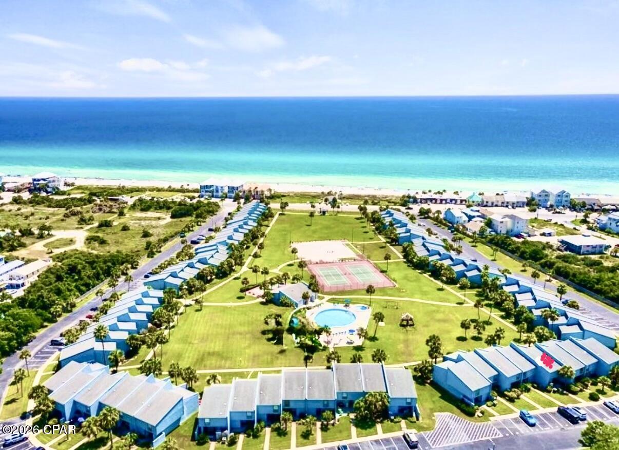 SLEEPS 10! These Condos on the coveted west end rarely come on the market, especially with a private dedicated beach  & private gazebo with viewing area to relax and enjoy the view! This updated unit is 4th from right on bottom of ''U'' with wide panoramic view of the green! Located 350' from the Gulf.

The Sellers thought this was going to be their forever home so it was never used as a rental! This fully renovated unit has new lighting throughout.  Kitchen has custom tile backsplash w/ 15'' deep solid wood white cabinets w/ soft-close/deep drawers w/ dove-tailing combined w/ a beautiful quartz countertop. Custom solid wood beadboard added on adjacent wall to blend w/ existing. Deep stainless steel sink w/ dimmable light above, newer dishwasher, custom pots & pans drawers, too! Whole home was custom painted in 2024 w/ upgraded scrubbable paint & 6'' baseboards! Stairwell updated in 2024. All doors and windows are solid wood trimmed. Condo faces South to get full light all day. Back wall has 90% UV protection screens even tho the sun does not beam in. Nice sized LR with sofabed and enough room to add an extra chair. The 16' high ceiling adds so much room to this already nice sized condo! Don't miss the tongue and groove solid wood ceiling! Spectacular feeling when entering! DR seats 6 with a bench that can be added for extra guests! 1/2 bath downstairs with new cabinet and lighting. Laundry room behind it with full sized W/D. Laundry room exterior door is 36'' wide as is front door. Storm door added to enjoy fresh air.  Large walk-in owners closet. Nest thermostat. Loft area has a queen Murphy bed with beams above to blend with LR area. Some electrical outlets moved for convenience. Large Primary BR with wood beams and bottom up/top down custom shades as well as ensuite bath with updated tile shower. Guest BR has white solid oak single bunk beds with queen bed. Some units have this room with glass windows looking down into the LR - this one is private! Both bedrooms have custom extra storage above closets as well as 10' ceilings! New carpet in bedrooms w/ upgraded padding. Both baths are renovated w/ new lighting, tile flooring, vanity cabinets w/ soft close drawers.  Guest bath has bathtub/shower combo. Patio in front for relaxing as well as large patio out back to enjoy the incredible view! There is 24-hour service available daily whether it be maintenance or office manager on site. Security guard on site throughout the week. The HOA maintains the outside painting & roof, with internet, trash and water included. Sunnyside Beach & Tennis Resort is a tranquil escape located on the quiet side of PCB. Situated amidst lush greenery, this tropical paradise encompasses 18 acres within 350 ft. of the emerald waters and sugar white sand beaches. The unique quality of this resort is the private pedestrian beach access. The underpass is a well-lit tunnel under Front Beach Road which leads to the large gazebo and boardwalk that sits on the white sandy beach! The complex amenities include: tennis courts, shuffle board courts, 2 pools (one for the little ones), a playground, and a clubhouse which features: free Wi-Fi connectivity, ping-pong table, and pool table and its very own private view of the Gulf. Come see this gem of a condo!  Make it your home! No RV parking, only boat trailers and enclosed trailers, maximum 30' located in private lot beside condo. (Some personal knick knacks do not convey)