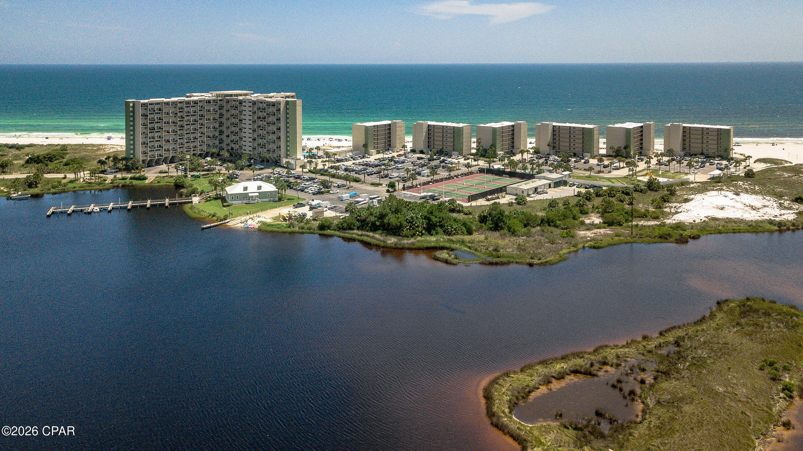 Experience the best of coastal living in this beautifully positioned two-story condominium at Pinnacle Port, ideally located on the highly desirable west end of Panama City Beach. Offering a rare blend of Gulf-front and lakeside access, this property delivers a unique lifestyle surrounded by both the emerald waters of the Gulf and the tranquility of Lake Powell.

The main level features a bright and open living space that flows seamlessly to a private balcony overlooking the lake, creating the perfect setting for relaxing or entertaining. The kitchen is thoughtfully designed with both style and functionality in mind, while a convenient half bath is ideal for guests.

Upstairs, two spacious bedrooms provide comfort and privacy, each offering its own scenic perspective. The primary suite includes access to a private balcony, while the guest bedroom captures stunning coastal views. This well-designed layout maximizes both space and functionality.

Residents of this gated community enjoy an impressive array of amenities, including direct beach access, multiple pools, tennis and shuffleboard courts, a fitness center, and access to Lake Powell with a boat launch and dock. Bordering Camp Helen State Park, the setting offers a peaceful, natural backdrop while remaining just minutes from the shopping, dining, and entertainment of 30A and Pier Park.

Whether you are searching for a primary residence, vacation getaway, or investment opportunity, this property presents an exceptional opportunity to enjoy the very best of Panama City Beach waterfront living.
