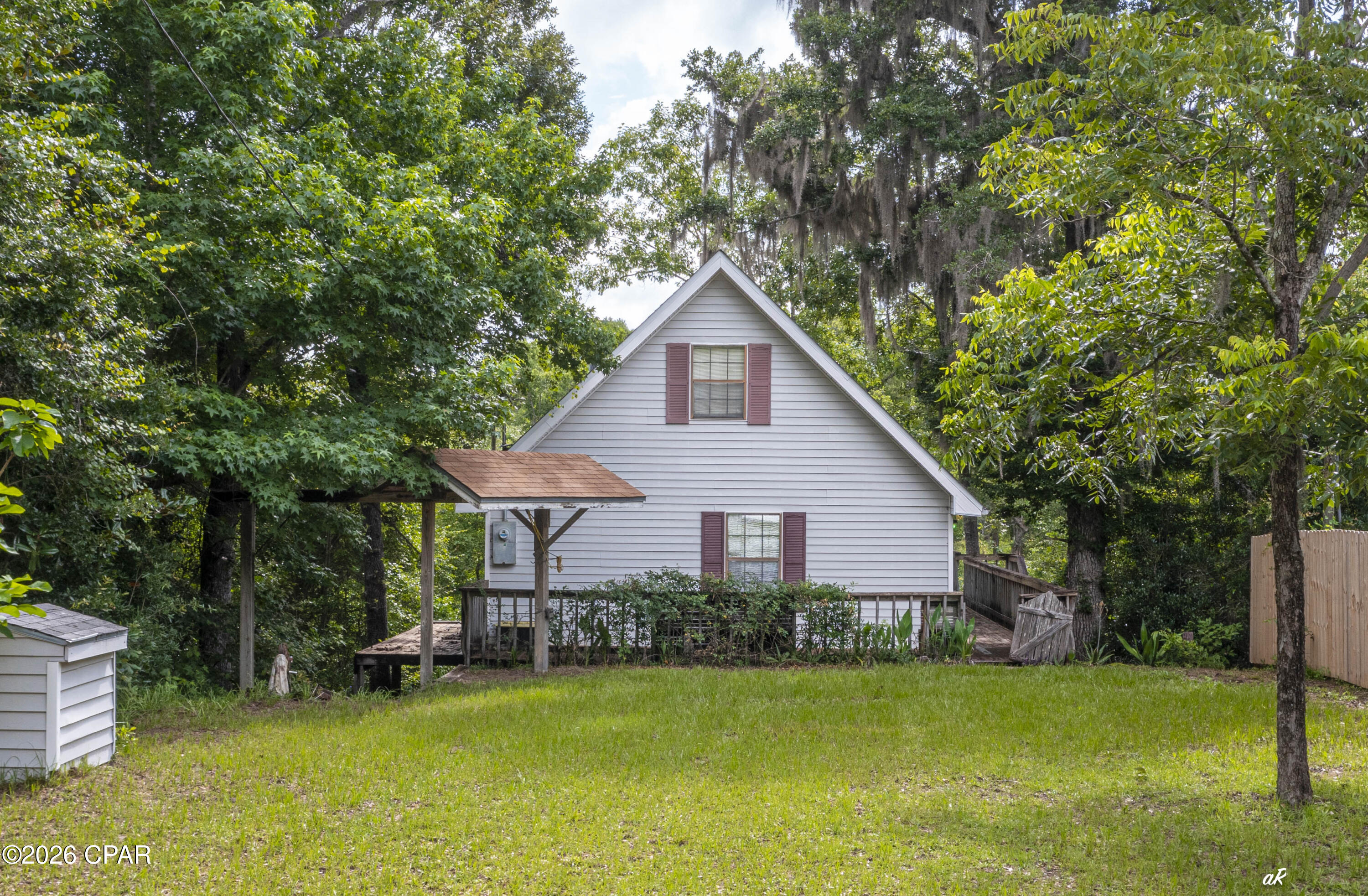 Enjoy 50 feet of beautiful waterfront on the Chipola River with this unique river retreat loaded with features. This three-level home offers a private bedroom and bath upstairs, while the main level includes a spacious kitchen, living area, and primary bedroom with sliding glass doors leading to a covered porch overlooking the river. The lower level features a heated and cooled camp area with a summer kitchen, pecky cypress walls, and a workshop space. Outside, enjoy a private dock with a fish cleaning station. Perfect for relaxing, fishing, and enjoying river life.