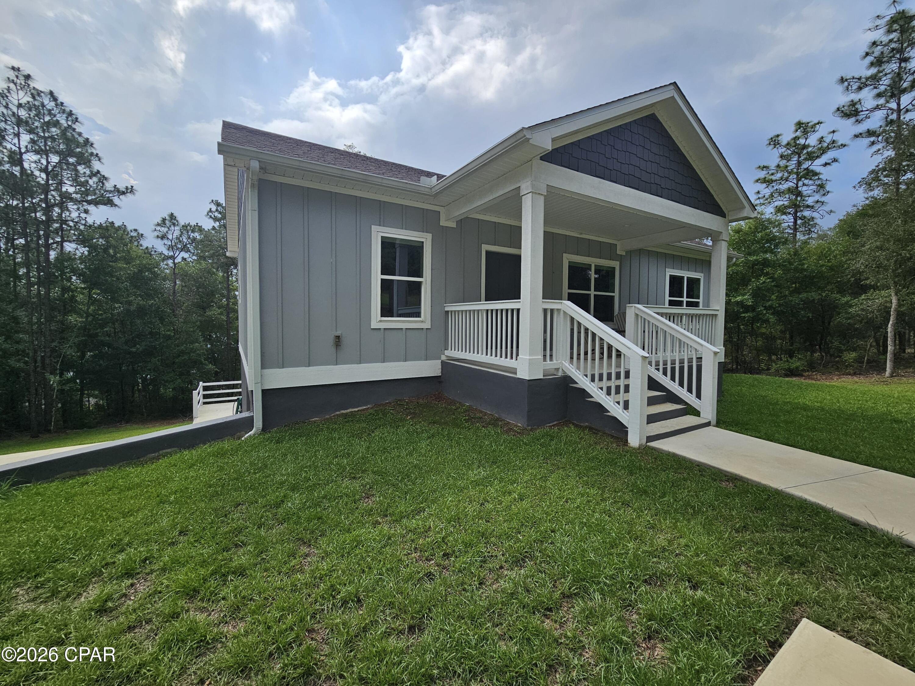 This has to be one of the nicest waterfront houses in Leisure Lakes, and the only one with a full basement. This was a custom build and only about 2 years old. It has plenty of room with 3 bedrooms and 3 full bathrooms for family and guests. No corners were cut in the construction phase including downstairs that has a recreation room, full bathroom, bedroom, and a garage door to pull in your  four wheelers, ATVs, golf cart and whatever needs covered storage. The concrete driveway winds down to the front porch, or more parking is available adjacent to the massive concrete patio. The front porch is covered that offers a nice view of sunsets over a landscaped lawn that includes many pallets of centipede sod. Upon entry there is a sitting area with double windows that looks so relaxing for reading or quiet time. The modern kitchen is huge and features granite counter tops and island, soft touch closing cabinet doors, large stainless steel sink, wall oven, big microwave, and a cook top that has a popup downdraft to remove any heat and smoke from cooking. Eat at the island or at the table beside a large window pane with views of the spring-fed lake. At lakeside is a dock with a platform with engineered boards created to last. The main master suite is on the first floor just off the sitting area. It has 2 windows to let in extra lighting and faces to the west, a walk-in closet with wire shelving and the only room with carpeting. All other flooring is durable LVP. The suite bathroom has granite over the counter, and the tile shower has sliding glass doors, along with a corner seat and a recessed space for soap and shampoo. The utility room is large enough for a washer, dryer and storage cabinet. There is a set of pull-down steps that go into the attic, with much of the space has wood flooring so it can be walked on and used for storage of seasonal items. There is an additional bedroom and full bathroom just off the dining area for family or guests. Downstairs has a game room that the owners used to set up a pool table. The door in the game room leads out to the concrete patio and a great place to grill, hang out and entertain. There is also a bedroom and full bathroom that has a shower with a seat. Upon opening the garage door there is plenty of room for a work bench, tools, lawn equipment and other items that would normally go into an outside shed. There is another closet under the stairway. Another room is where the air handler and hot water heater is set up. There is also shelving and more storage area. All of this is in the security gated subdivision about 30 minutes north of Panama City, just off Hwy 77. Gate guards are on duty weekdays, and residents have a unique code for entry when guards are not present.