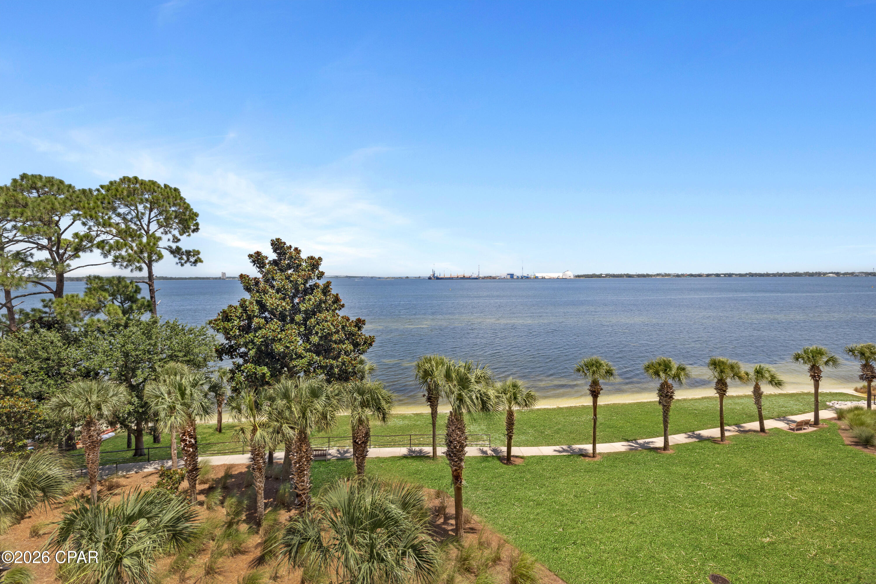 THREE BEDROOMS. THREE BATHROOMS. BAYFRONT LIVING ON THE QUIETER SIDE OF PANAMA CITY BEACH. 
Magnolia Bay Club Unit 404 is a freshly painted three-bedroom, three-bathroom residence offering a split floor plan, large bayfront balcony, and central fourth-floor position overlooking St. Andrews Bay with views toward the Hathaway Bridge. Professionally deep cleaned and move-in ready, the interior features wood flooring throughout the main living areas, tile flooring in the kitchen, hallway, and bathrooms, and an open-concept layout with space for a dining table. The kitchen includes stainless steel appliances, ample workspace, and a direct connection to the living area, while the washer and dryer are also included.
The spacious primary suite features sliding glass door access to the balcony, along with a large bathroom offering a double vanity and walk-in shower. The seller is replacing the fogged glass panel in the primary bedroom window and door assembly prior to closing. The split-bedroom design creates additional separation between sleeping areas. The guest bedroom on the right includes a pocket door, allowing it to function as a bedroom, home office, or flex space. The guest bedroom on the left has its own private full bathroom with double vanities, creating a true second suite.
The living room opens through sliding glass doors to the large balcony, where the fourth-floor position provides sunrise views across the bay, illuminated nighttime views of the Hathaway Bridge, and the sound of the water along Magnolia Bay Club's private bay beach below. Fourth-floor residences also feature a solid balcony wall rather than metal railings, providing additional privacy and a greater sense of security. The enclosed design may be especially appealing to owners with small pets because there are no railing openings.
Magnolia Bay Club is a gated bayfront condominium community with no short-term rentals permitted. Community amenities include a bayfront pool, private beach, dock, kayak access, fitness center, meeting room, BBQ grills, dumpster service, and maintained common grounds. The property is located approximately one mile from Publix and approximately three miles from the beaches of Panama City Beach.
Monthly condominium association dues are currently $1,066.64 and include water, sewer, trash service, pest control, and maintenance of the common areas. All information is deemed reliable but not guaranteed; buyer to verify if important.