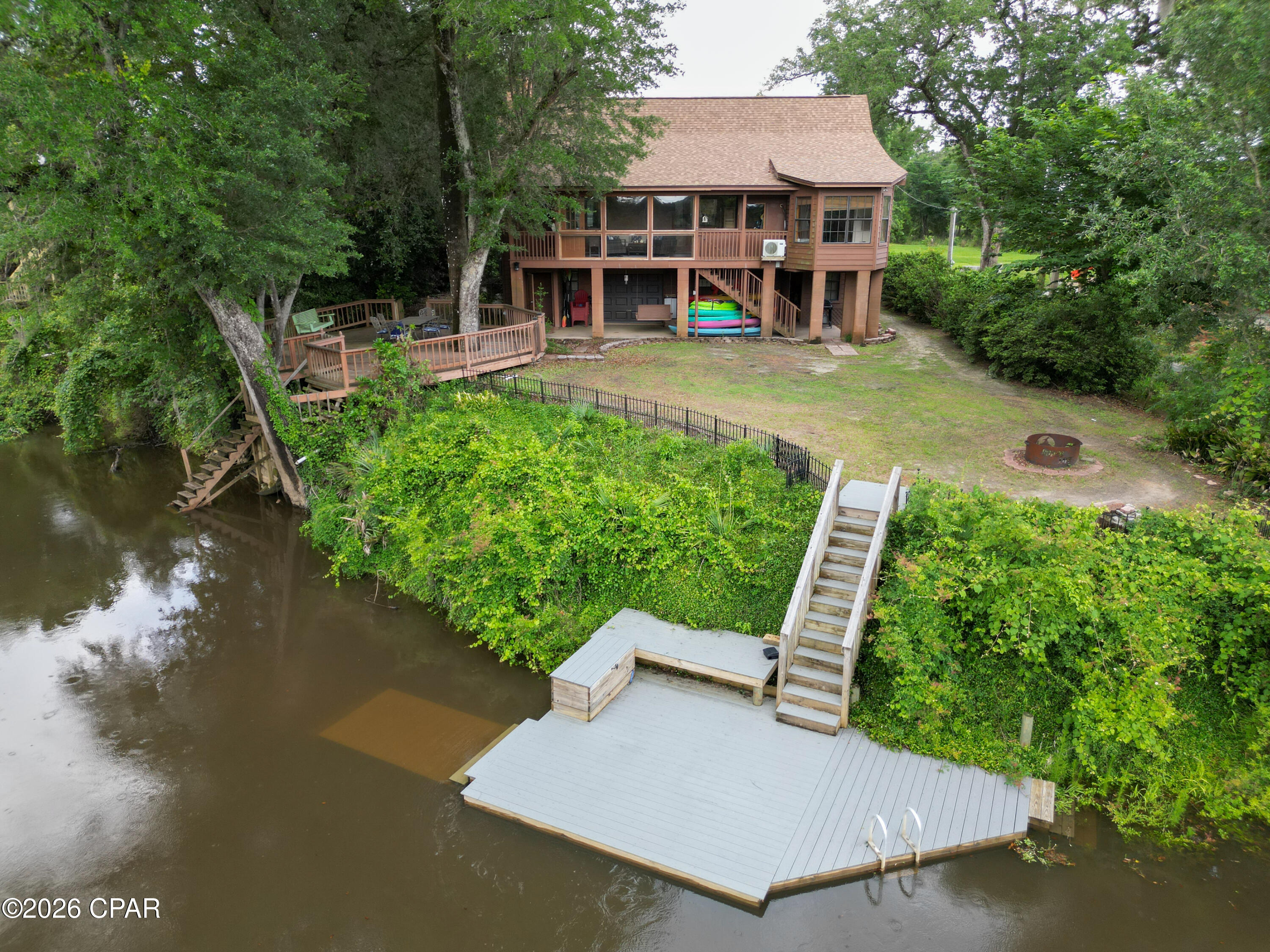 Welcome to riverfront living on the beautiful Chipola River! This charming home offers peaceful river views right from your private back deck, creating the perfect place to relax, entertain, or simply enjoy the natural surroundings. With two access points to the river, this property is ideal for those who love fishing, kayaking, boating, or spending time outdoors. Inside, the open-concept main living area features a stunning large stone fireplace with gas logs, adding warmth and character to the heart of the home. The main floor includes two bedrooms, including a spacious master suite with access to the back deck overlooking the river. The master bath features a large jetted tub and separate shower, offering a relaxing retreat. Upstairs, you'll find a loft bedroom with a half bath, providing additional space for guests, a home office, or a cozy getaway. The home also includes an elevator for added convenience. Downstairs, the well-lit garage offers plenty of room for a boat, ATV, storage, and more. Whether you're looking for a full-time residence, weekend retreat, or riverfront getaway, this Chipola River property is one you'll want to see!