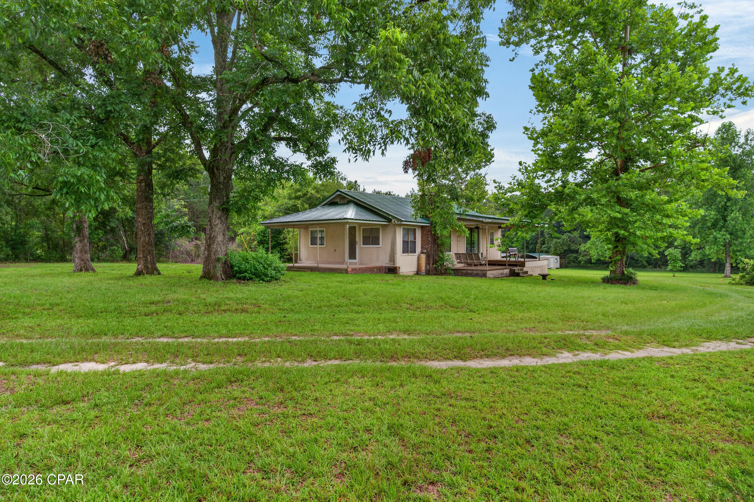 Escape to the peace and privacy of country living with this secluded cabin on acreage, complete with a recently surveyed parcel, pond, partial fencing, circular driveway, and plenty of space to enjoy the outdoors. Spend your mornings on the covered porch featuring a porch swing, ceiling fan, and bench seating while watching the wildlife, including deer, wander through the property. Inside, the cozy cabin is in livable condition and offers a comfortable living area with a kitchen pass-through and breakfast bar, creating a nice connection between the kitchen and living room while still keeping each space defined. The home could use some TLC, giving buyers the opportunity to make it their own while enjoying the property right away. Outside, you'll find a detached garage, workshop, tool shed, and multiple covered pole barns with concrete foundations, providing excellent space for equipment, boats, outdoor toys, hobbies, projects, and storage. Outbuildings have electric, adding even more function for workshop use, hobbies, and storage needs. With abundant wildlife, a peaceful setting, and practical improvements already in place, this property is ideal for anyone looking for a private country retreat with room to spread out.