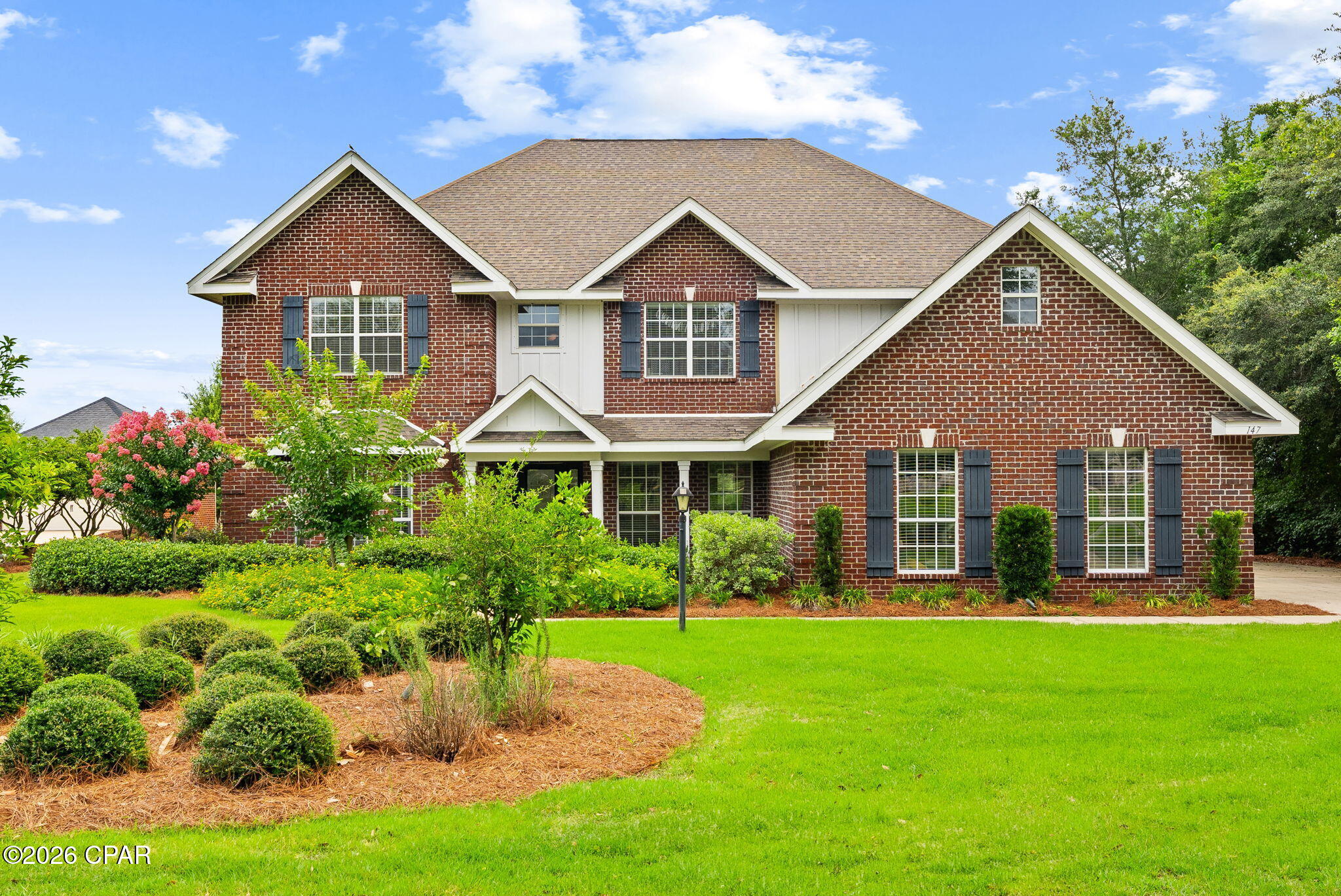 ASSUMABLE VA LOAN AVAILABLE WITH AN INCREDIBLE 2.25% INTEREST RATE!** 

Rarely does a property offer this much space, privacy, and waterfront lifestyle in one package. Set on 1.14 acres with approximately 110 feet of frontage along the crystal-clear waters of Lake Merial, 147 Lake Merial Shores is a 4,182-square-foot waterfront retreat designed for those who believe home should be the gathering place for every holiday, celebration, and family milestone. Featuring six bedrooms, a bonus room, three-car garage and expansive indoor and outdoor living spaces, this remarkable estate is where unforgettable lake memories are made. 

From the moment you enter, soaring ceilings and beautiful hardwood flooring create an impressive first impression. To the left of the foyer, a stunning floor-to-ceiling custom library provides the perfect setting for a private office, reading retreat, or study. The private library showcases a custom rolling ladder that glides effortlessly along the entire room. Formal living and dining spaces offer flexibility for gatherings, while a dedicated dining room area with a private bar creates an inviting atmosphere for hosting family celebrations and holiday dinners. The grand living room serves as the heart of the home, featuring dramatic 18-foot ceilings and expansive windows that frame picturesque views of the lake beyond. A beautiful wood burning fireplace creates a warm focal point, flanked by custom built-in cabinetry that provides both elegant display space and functional storage while enhancing the room's timeless character. 

The well-appointed kitchen offers abundant cabinetry and storage throughout, including an extended custom storage area adjacent to the eat-in kitchen space. A conveniently located half bath near the kitchen enhances the home's thoughtful design and provides added comfort for guests during gatherings and special occasions. The spacious primary suite is located on the first floor, creating a private retreat separate from the additional bedrooms. 

Upstairs, you'll find five generously sized bedrooms, two full bathrooms, and a massive bonus room large enough to serve as a home theater, game room, fitness area, or recreation space large enough for a pool table. 

Step outside and experience the true beauty of Lake Merial living. Outdoor living takes center stage with a covered back patio and an expansive paver terrace designed for entertaining and relaxation. A private paver pathway meanders through the backyard to the lakefront, creating a seamless connection to the waterfront lifestyle. Whether you're launching a kayak, casting a line, enjoying a sunset cruise, or simply unwinding by the water, Lake Merial becomes an extension of your backyard. The meticulously maintained grounds create a park-like setting, offering plenty of space for outdoor entertaining, backyard barbecues, family gatherings, and making memories with friends and neighbors. Imagine spending Independence Day watching fireworks illuminate the lake, enjoying golf cart rides through the neighborhood, and ending the evening gathered around the water with family. This is more than a home--it's a lifestyle. 

Lake Merial is one of Bay County's most sought-after waterfront communities, centered around a beautiful 300-acre spring-fed lake known for its clear waters and year-round recreational opportunities. Residents enjoy community events, walking trails, green spaces, and food truck nights. 

Defined by its scale, waterfront setting, and enduring craftsmanship, 147 Lake Merial Shores stands as a distinguished Lake Merial residence, offering the space, privacy, and versatility to accommodate generations while creating an exceptional backdrop for everyday living. As one of only a handful of homes of this size situated directly on the water within Lake Merial, this remarkable property represents a rare opportunity to own one of the community's most significant waterfront estates.