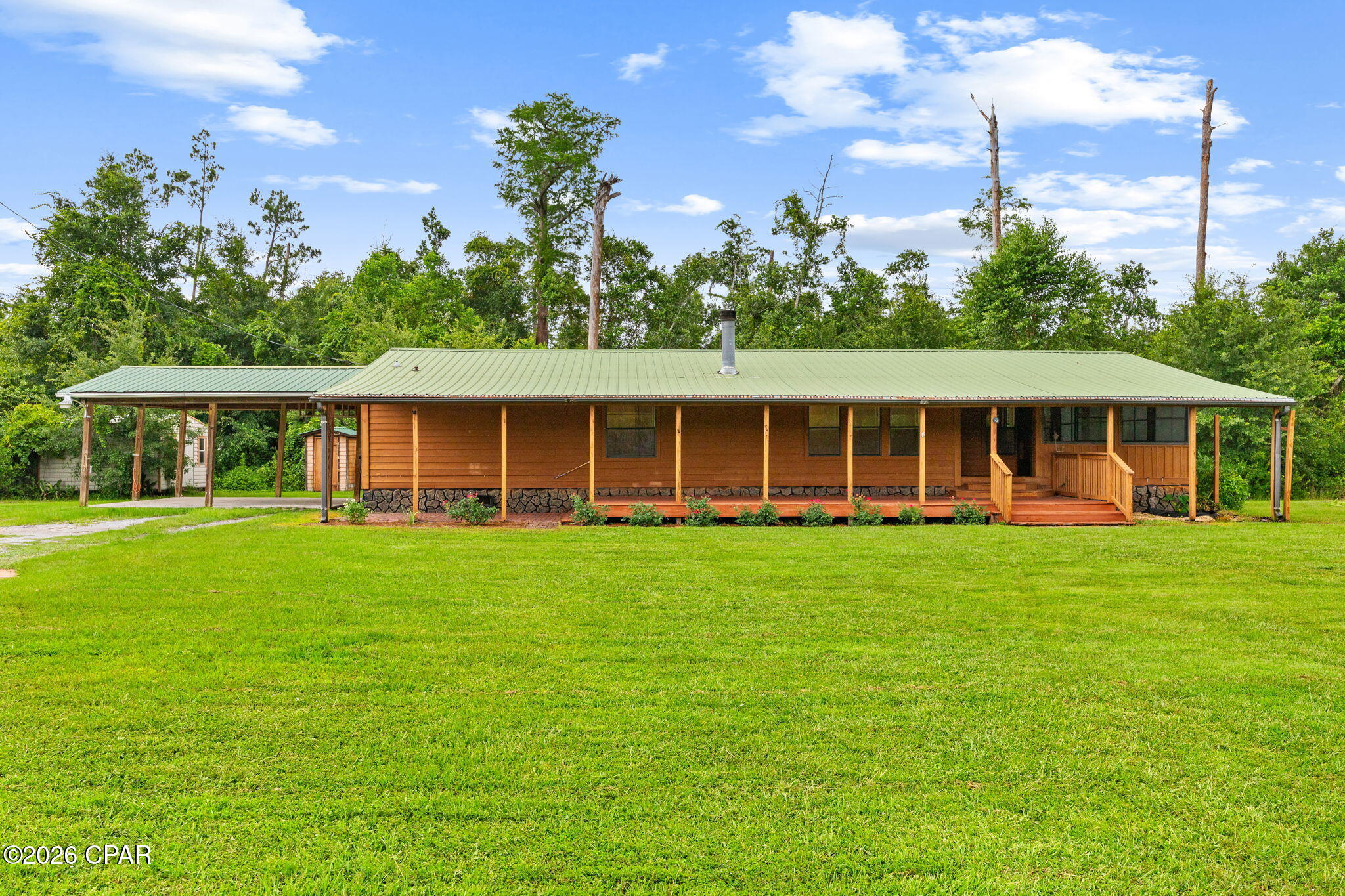 Welcome to 8306 Highway 2301 in Youngstown, where peaceful country living meets comfort and convenience. Situated on approximately 1.12 acres surrounded by mature trees, this well-maintained 2-bedroom, 2-bath home offers approximately 1,606 heated and cooled square feet with a functional, single-level layout and plenty of room to enjoy the outdoors.

Built in 1999, the home has received several updates, including luxury vinyl plank flooring throughout and interior paint completed within the last three years. The inviting living room features a beautiful woodburning, white stone fireplace accented by a wood mantel, creating a warm and welcoming focal point. The spacious kitchen offers stainless steel appliances, a center island, and plenty of room for everyday living and entertaining.
Just off the kitchen, a sliding glass door leads to a screened porch overlooking the property's natural surroundings; the perfect place to relax and enjoy the peaceful setting. The home also features a large covered front porch (15 x 53), providing additional outdoor living space. The spacious primary suite features two closets and a well-appointed ensuite bathroom with dual vanities, a large soaking tub, and a separate walk-in shower.

Outside, the property includes a two-car carport and a separate storage building for added convenience. With approximately 1.12 acres, mature trees, and no homeowner's association, this property offers privacy, space, and the flexibility to make it your own.

This property is also available for long term lease ($1600/month).  Please see MLS 792835