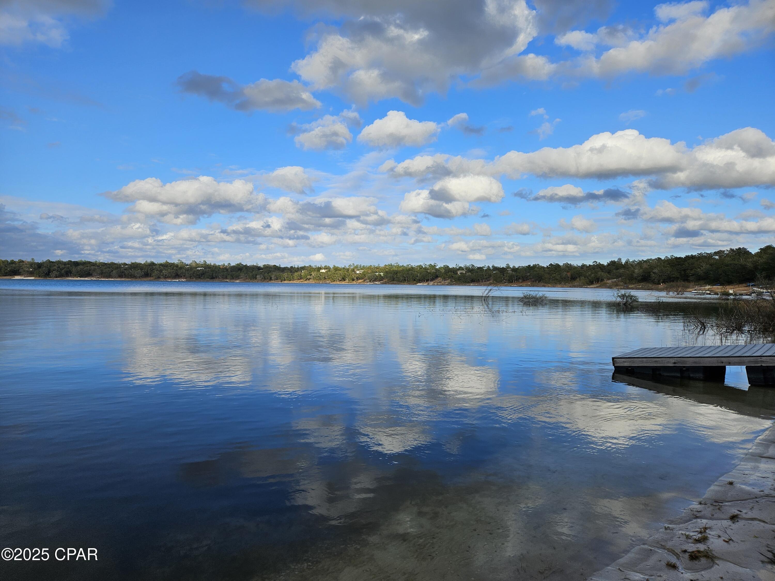 This is a wonderful waterfront lot in the security gated subdivision of Leisure Lakes, just off Hwy 77. Located about 30 minutes north of Panama City, this shaded lot by oak trees has with a gentle slope down to the crystal clear water. Located on the southeast side of the lake, this is a good location to see the beautiful sunsets that other residents enjoy in the evenings. The lot has been only partially cleared so the new owner can sculpt the lot depending on the dimensions of the proposed house and decking. Docks are allowed up to 30 feet long, according to the covenants. The recreation area provides plenty to do as the photos show. The recreation area has a tennis court, basketball court, swimming pool, men's and women's restrooms, grill stations, concrete boat launch, covered pavilion and more. There is a security gate and live guards are on duty weekdays. HOA dues are $250 each year. Come enjoy lakefront living!