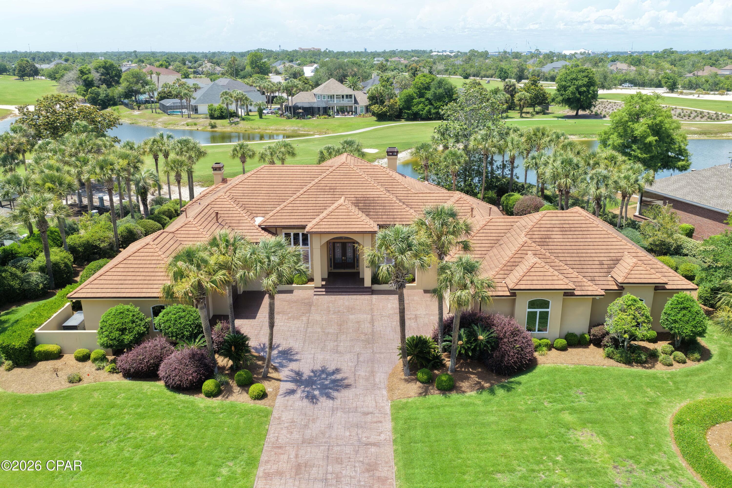 Discover 3500 Dragon's Ridge Road, an exceptional estate home that perfectly blends luxury, comfort, and durability in a breathtaking golf course setting within the gated community of Bay Point Legend Hills. Situated on a rare double lot, this custom-built, one-owner residence offers more than 4,600 square feet of thoughtfully designed living space all on one level, featuring soaring 10- to 16-foot ceilings, abundant natural light, Andersen windows and doors, solid core doors, crown molding, plantation shutters, and quality craftsmanship throughout. Stunning curb appeal welcomes you home with beautiful landscaping and wide driveway, concrete tile roof, and oversized three-car garage. Inside, enjoy expansive views of the 10th hole, 11th fairway, picturesque ponds, and unforgettable sunsets from the moment you enter. The spacious layout includes elegant living and dining rooms, a private office, and a gourmet kitchen equipped with Thermador appliances, Sub-Zero refrigerator, induction cooktop, Bosch convection microwave, Viking warming drawer, and an inviting family room with fireplace and custom wood feature wall opening to the outdoor living area. The resort-style backyard is designed for relaxing and entertaining with a sparkling pool, covered patio, and fenced pool deck overlooking the golf course and water views. The private primary suite serves as a true retreat with a sitting area, oversized walk-in closet, dressing area, and recently updated bath featuring dual vanities and a custom wheelchair-accessible walk-in shower, along with direct access to the pool and hot tub. Two guest bedrooms with en-suite baths, a walk-in laundry room, and guest half bath complete the main living wing. A separate private wing offers incredible flexibility with a dedicated media room featuring projector screen, bar area, wine cooler, bonus living space, exercise room, full bath, private entrance, and oversized one-car garage/workshop, making it ideal for a mother-in-law suite or guest quarters. Additional highlights include four HVAC units replaced within the last five years, two gas water heaters replaced in December 2025, whole-house generator, roll down hurricane shutters, and gas furnace for year-round comfort and peace of mind. Residents of Bay Point enjoy resort-style amenities including a Jack Nicklaus-designed championship golf course, full-service marina, dining and entertainment at Bar 72, and convenient access to boating, shopping, dining, top-rated schools, and the sugar-white sands of Panama City Beach. This remarkable legacy property offers the perfect combination of elegance, functionality, and coastal lifestyle living.  Call today for your private showing!