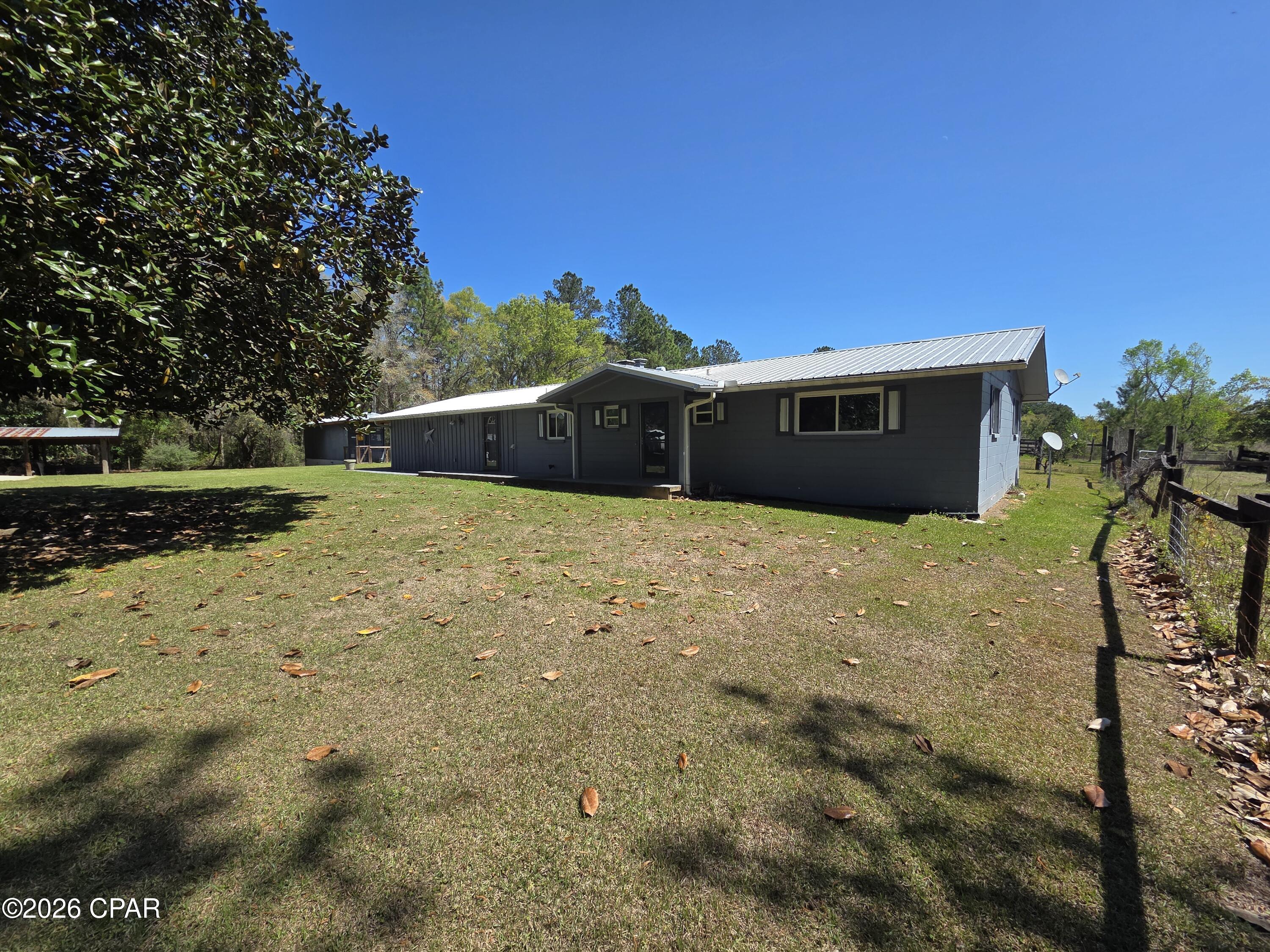 3/2 home on 11.15+/- acres. Come put your personal touches on this spacious home offering a kitchen with plenty of storage, bar for extra seating. Living area with wood burning fireplace and dining area. Split floorplan with 2 bedrooms and 2 baths on one side and large 3rd bedroom on the other. Bonus space could be office or kids play area. Laundry area. Screened in back porch. Storage room. Covered parking at the house. Large pole barn for extra parking or storage for your RV. Covered lean to for wood storage and equipment.  Storage container and additional storage building. Extra large pole barn has screened in area for entertaining, cook outs. Full bathroom. 2 horse stalls. Plenty of room for hay storage. Additional storage room on back. Property is fenced. There are 2 fenced in areas to keep animals close to barn. Property has 2 wells and 2 septics. Electric gate at front of property  Paved road frontage. Situated in the center of the Florida panhandle for easy access to Panama City Beach to the south, Dothan, AL to the north, Tallahassee to the east and Pensacola to the north. This is the perfect opportunity for you to have the mini farm you've always dreamed of.