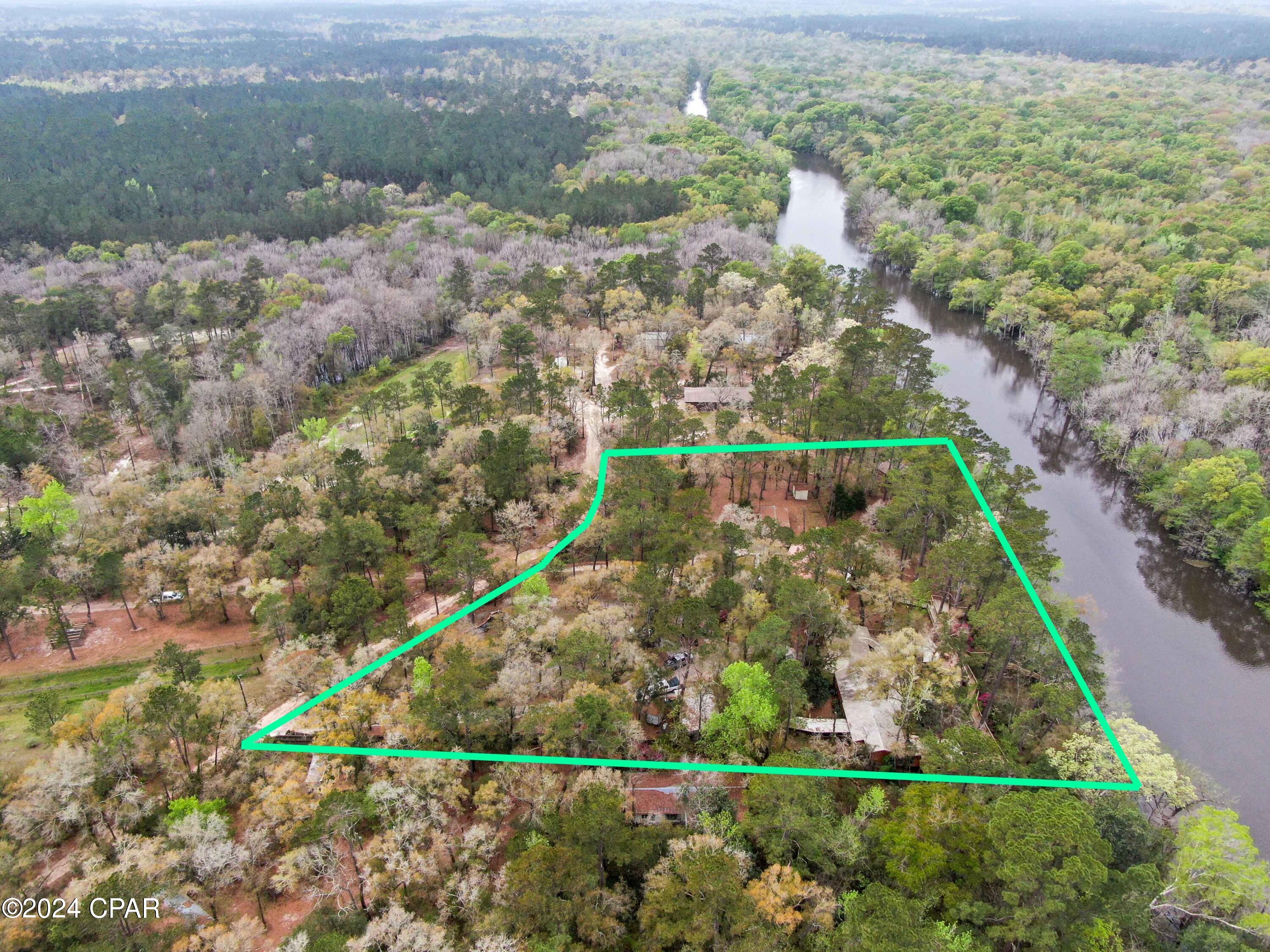 Situated gracefully along the serene banks of Holmes Creek, this Creek Front Estate presents a distinguished opportunity for refined living within a tranquil natural setting. Encompassing nearly 2.5 acres of verdant landscape, this property comprises two distinct residences, embodying a harmonious blend of comfort and functionality.

The primary dwelling, characterized by its timeless architectural design, accommodates four bedrooms and three full baths, thoughtfully arranged to provide spacious living areas conducive to both relaxation and entertainment. Embracing the creek view, multiple rooms within the main home offer glimpses of the serene waters, enhancing the connection to nature and fostering a sense of serenity throughout.

Boasting two fully equipped kitchens and a collection of interior and exterior fireplaces, hosting gatherings and intimate gatherings alike is effortlessly facilitated within this abode. The expansive wooden porch and deck system extend an invitation to outdoor leisure, while the recreation room, ingeniously constructed around a majestic oak tree, serves as a distinctive focal point, seamlessly integrating the natural surroundings with modern living.

The secondary residence, featuring two bedrooms and two baths, complements the estate with its understated elegance and functionality. A spacious sunroom overlooks the tranquil creek, offering an idyllic retreat for quiet contemplation or leisurely gatherings. Outdoor amenities include a pergola and expansive open deck, perfect for alfresco dining and relaxation amidst the enchanting landscape.

Completing the estate are several outbuildings, multiple stone firepits, and a captivating stone waterfall system, each contributing to the property's charm and utility. Holmes Creek, renowned for its abundance of natural springs and access to the Choctawhatchee River, enriches the living experience with opportunities for exploration and recreation.

Conveniently located less than 30 minutes from Panama City Beach, this Creek Front Estate strikes a balance between formal elegance and natural serenity, offering an unparalleled opportunity to embrace refined living amidst the beauty of Holmes Creek. Experience the timeless allure of this distinguished property, where every detail has been meticulously crafted to elevate the essence of home.