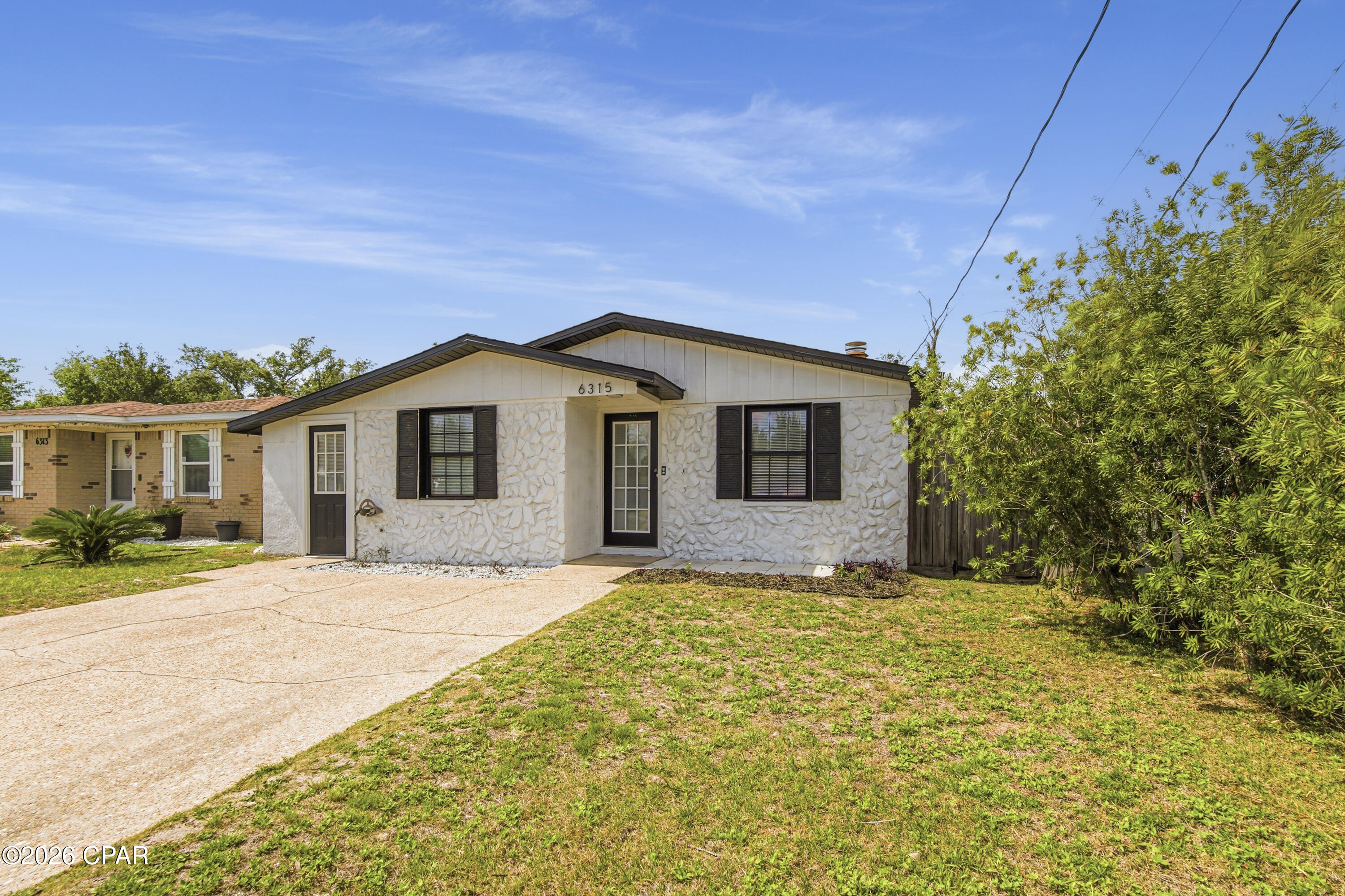 Welcome home to this beautifully updated 3-bedroom, 2-bath rental offering the perfect mix of modern style and everyday comfort. Conveniently located just minutes from Tyndall Air Force Base, shopping, dining, Walmart,  and local restaurants, this home makes commuting and daily errands easy. Inside, you'll find a bright open-concept layout with plenty of natural light and a cozy fireplace that creates a warm, welcoming atmosphere. The main living areas feature luxury vinyl plank flooring, while the freshly painted exterior adds great curb appeal. The updated kitchen is designed to impress with stylish cement countertops, a clean white backsplash, colorful cabinetry accents, stainless steel appliances, and a large island complete with a built-in wine cooler. It flows seamlessly into the dining area, making it perfect for entertaining or everyday living. Both bathrooms have been refreshed in recent years, including updated toilets and an upgraded primary shower, giving the home a clean and modern feel throughout. Step outside and enjoy the oversized fully fenced backyard featuring a large patio that is ideal for relaxing, entertaining guests, or enjoying quiet evenings outdoors. A powered storage shed provides extra space for hobbies, tools, or additional storage needs.