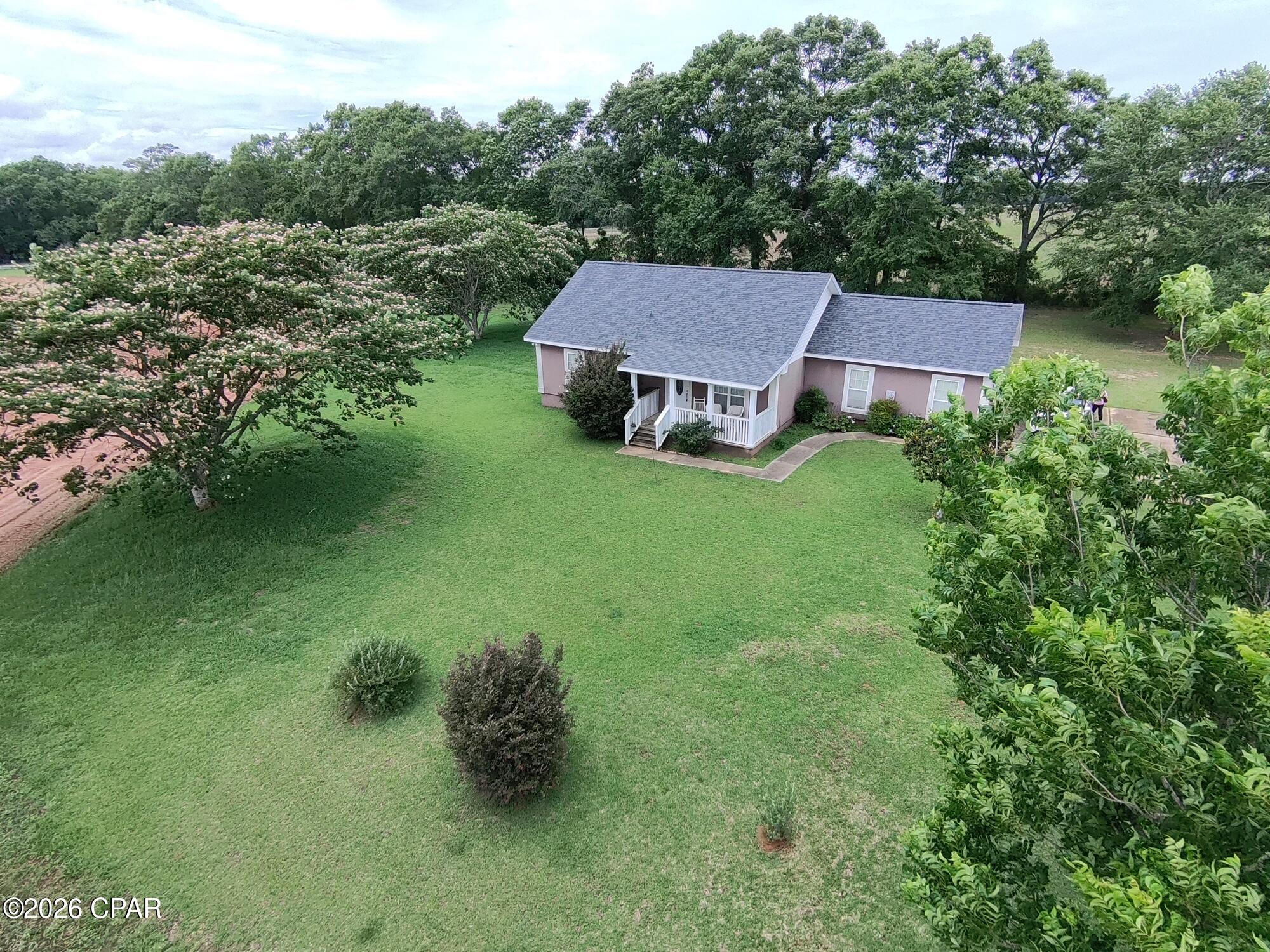 Welcome to peaceful country living in Graceville, Florida! Conveniently located off of HWY 77 just north of town and approximately a 1/4 of a mile south of the state line. This beautifully maintained property offers privacy, comfort, and the quiet rural lifestyle so many buyers are searching for. Situated on 1.32 acres that is surrounded by larger property owners. This home is tucked away approximately 600 feet off the highway along a beautiful  hardwood fence row. With very minimal visibility from the road and a peaceful atmosphere, this property truly gives the feeling of living on 20 acres or more! Built in 2006, the home features 1416 square feet of living space with a spacious and functional 2-bedroom, 2-bath floorplan, complete with a 2-car garage. Inside the home you'll find an open concept combining the family room, dining area, and kitchen - perfect for everyday living or entertaining guests. Both bedrooms feature large walk-in closets, while the primary suite includes a private bath for added comfort and convenience. An inside utility/laundry room adds practicality to the well-designed layout. This home has been exceptionally well cared for and includes valuable upgrades such as luxury vinyl plank flooring throughout and a newer roof installed in 2018. The home is serviced by a private well and septic system, adding to the property's rural independence and appeal. Even better... All furnishings shown in the listing photos are negotiable, offering a potential move-in-ready opportunity for buyers seeking convenience and flexibility! If you've been looking for a quiet, well-maintained country home with privacy, charm, and room to breathe, this property is a must-see.