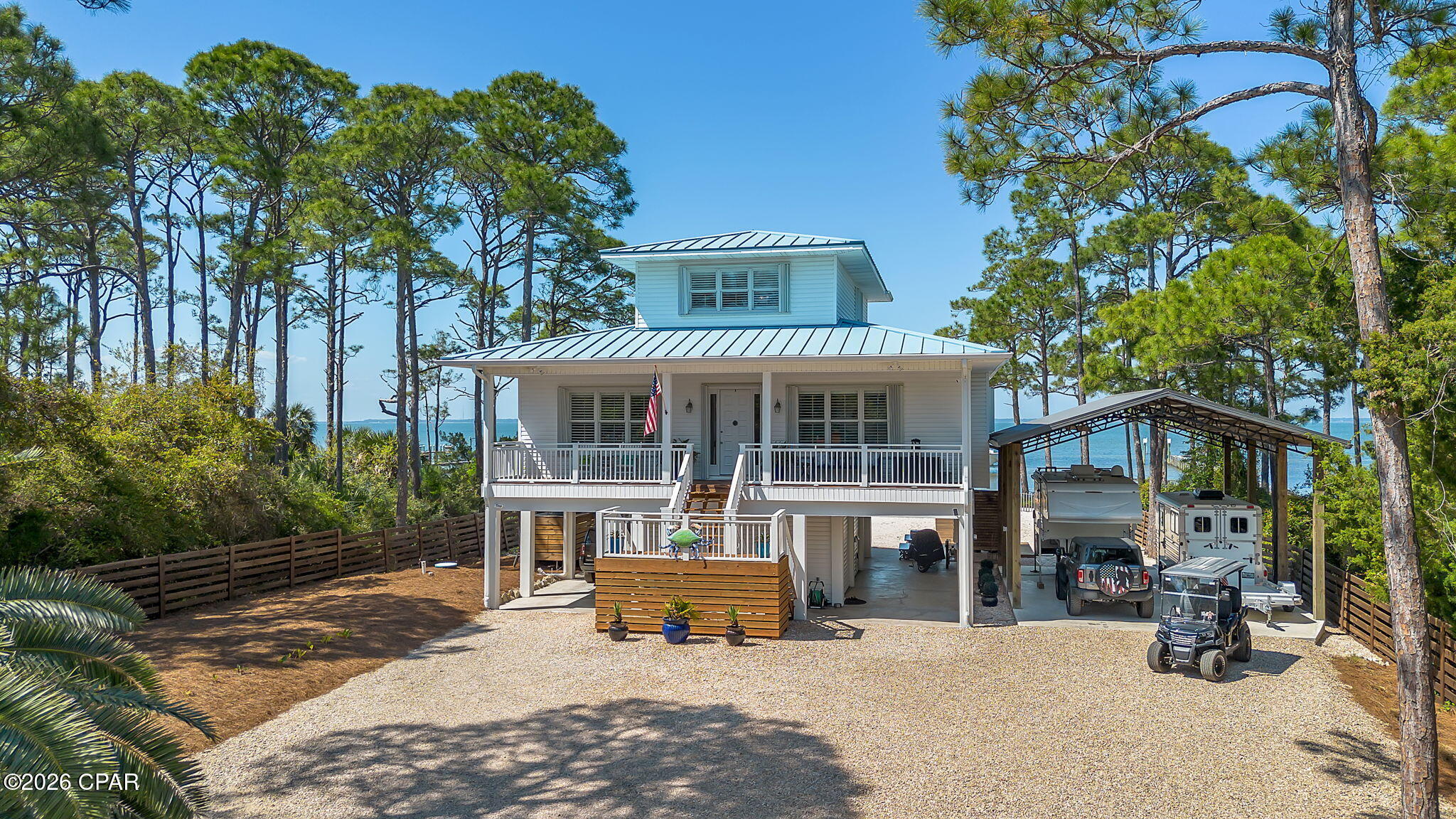 A private bayfront retreat designed for boating, sunsets, and elevated coastal living. Located in Watkins Cove on St. George Island, this gulf coast home offers 3 bedrooms, 2.5 baths, and 2,512 sq ft of heated and cooled space on a 0.67 acre homesite. Built in 2001 on concrete pilings, the property combines structural durability with refined waterfront design. Plenty of parking! The private dock is built for full-day water use, featuring a boat lift, water, electric, fish cleaning station, sandy beach entry, and space to accommodate jet skis and additional watercraft. Southwestern exposure delivers uninterrupted sunset views across the bay. Inside, the main living space is defined by 12 ft ceilings, real oak hardwood floors, and wide bay-facing sightlines. The kitchen is equipped with upgraded stainless appliances and bar seating for six, flowing into a living area with gas fireplace and direct access to a full-width screened porch. A separate living room. A cargo and passenger elevator to main floor/screen porch. The primary suite is positioned for privacy and views, with a full bay-facing picture window, walk-in closet, and bath with double vanity, garden tub, and separate shower. Two additional upstairs bedrooms include walk-in closets; one offers a private balcony overlooking the water. The ground level includes a concrete slab, workshop, and storage area. A 20x40 pole barn with RV hookup supports boat and recreational storage. Covered parking, gated entry, aluminum coastal fencing, and an expansive gravel drive allow for multiple vehicles, water sport equipment or boats Whole-house generator included. Located minutes from the center of St. George Island in private subdivison,and a short drive to Apalachicola and Eastpoint. Private, functional, and built for waterfront living, fishing, boating, sunset cruises or paddleboarding across the bay and sandy beach activities! Do not miss this immnaculate home.