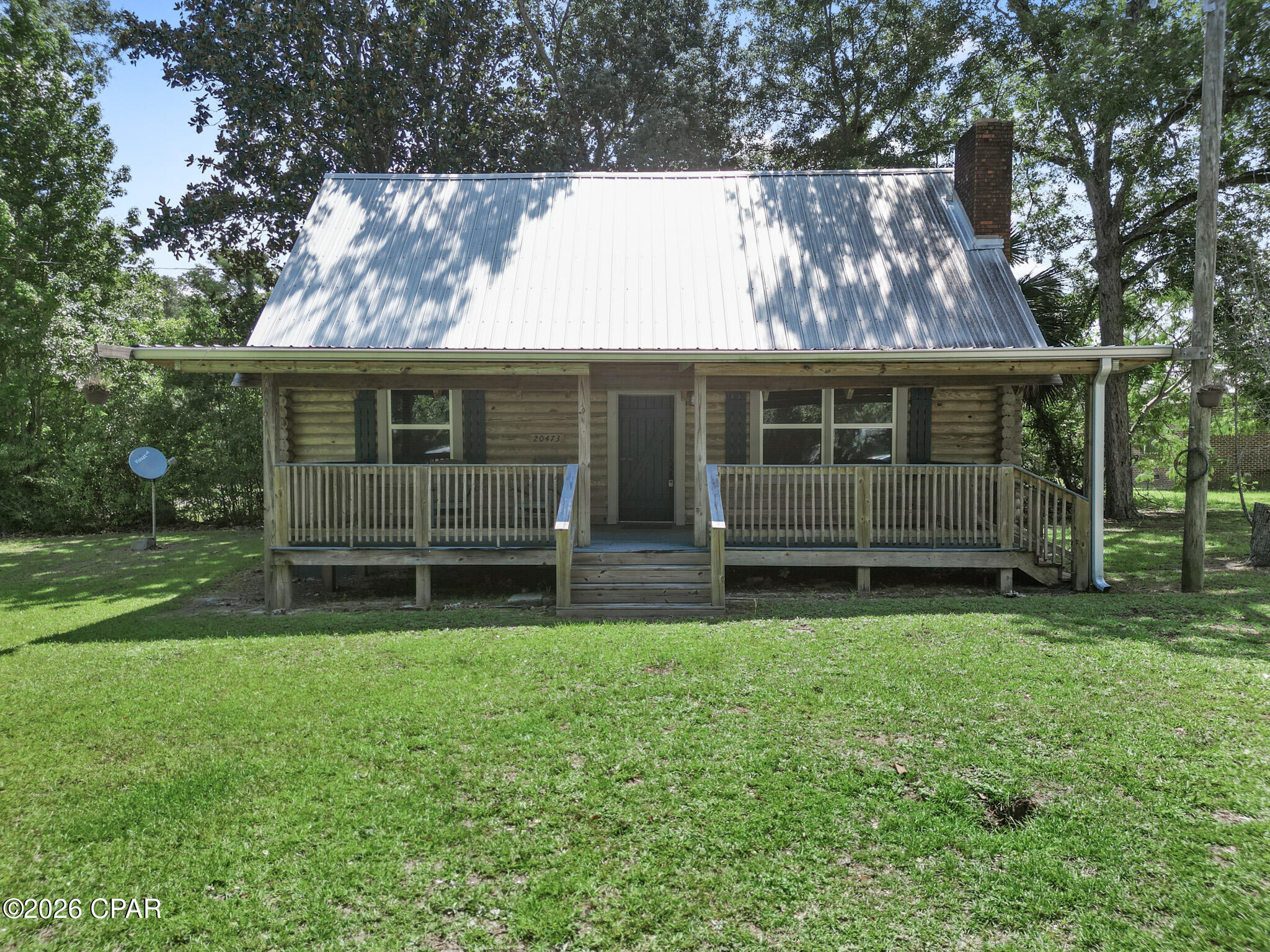 Welcome to 20473 NW Walnut Avenue, a one of a kind two story cabin in the heart of downtown Blountstown. From the moment you arrive, you'll appreciate the inviting front porch, soaring wood-beamed ceilings, and the warm character that makes this property feel truly special.

Inside, the open living, dining, and kitchen area creates the perfect place to gather, relax, or entertain. The main level includes a private bedroom and a conveniently located half bathroom, while the spacious loft upstairs features a full bathroom and flexible space for guests, a home office, hobby room, or additional living area.

The durable metal roof was installed in 2018, offering added peace of mind. Step outside and enjoy the convenience of being within walking distance of local restaurants, grocery shopping, and other downtown amenities. You'll also be about an hour from Panama City, Mexico Beach, and Dothan, Alabama, making it easy to enjoy the Gulf Coast, shopping, dining, and major employment centers while still experiencing the charm of small-town living.

Whether you're looking for a unique primary residence, a weekend getaway, or a property with potential for professional office use or short-term rental opportunities (subject to local zoning and approval), this cabin offers exceptional flexibility.

Properties with this much character don't come along often.