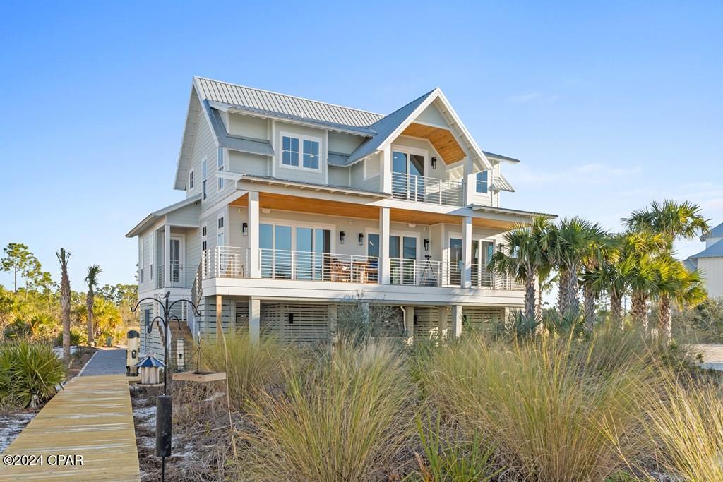 CUSTOM BUILT HOME with Sweeping Bay Views and Direct Beach Access in the Beautiful WindMark Beach gated community! This 4BR, 3.5BA is designed with a coastal aesthetics. This home boasts driftwood-inspired flooring that flows throughout, with a wall of windows & doors that flood the space with natural light and offers breathtaking sunset views. A natural stone fireplace creates a cozy ambiance, while beamed ceilings extend into the dining and kitchen areas. The spacious kitchen features a large island, durable soapstone countertops, GE Monogram appliances, which includes a 6-burner gas cooktop, griddle, and pot filler, surrounded by custom tile backsplash. A DO NOT MISS custom walk-in pantry, with built in beverage refrigerators, floor to ceiling shelving, along with butcherblock countertops.  Step outside to the expansive deck, perfect for dining or relaxing while enjoying the bay breeze. The deck features waterproof decking, Bluetooth-integrated speakers, and sleek modern stainless railings for a clean and contemporary look. Included on the main level is a sophisticated primary suite with private sunrise balcony, Carrara marble tile & notable spa-like features taking this home to another level. Upstairs offers a second bedroom with an ensuite bath. Two additional guest rooms and a flexible fourth bedroom that can serve as an office, bunkroom, or playroom. The home features a 3-stop elevator for easy access to all levels.  Outdoors, the beautifully landscaped grounds, a private boardwalk to the pet-friendly beaches and St. Joseph Bay. Additional first level amenities include a hot/cold outdoor shower, climate-controlled storage, garage parking, and a full water view outdoor entertaining area. Enjoy neighborhood amenities like a bayfront pool, boat docks, and nature trails, all within a golf-cart-friendly community. Located just minutes from fine dining, specialty shops, and a fitness center, this home offers unmatched coastal living and investment potential.