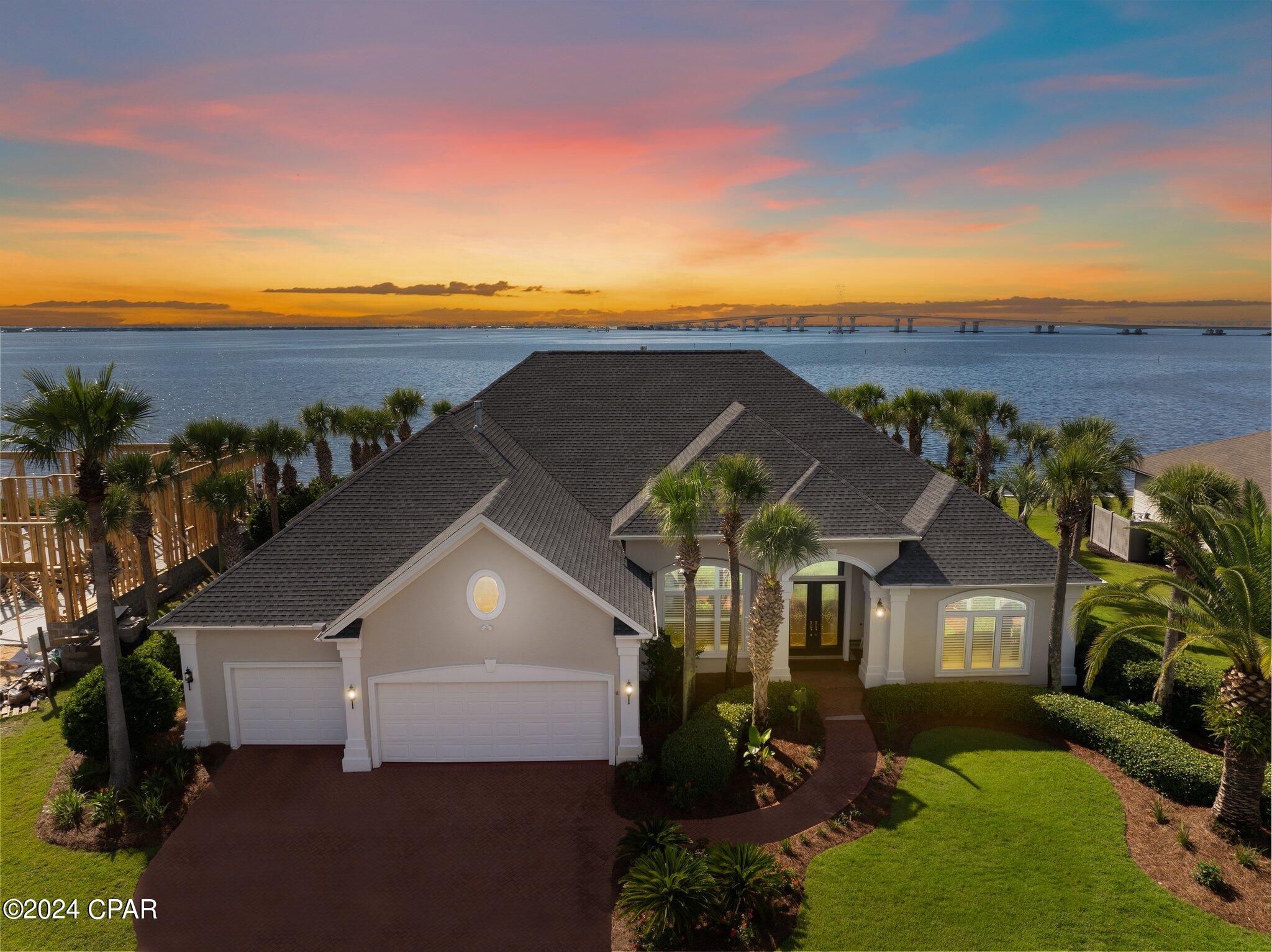 Experience unparalleled luxury in this pristine single story home with 4-bedroom and 3.5 bathrooms, overlooking the serene St. Andrews Bay. Spanning over 3,880 square feet of refined elegance, this property boasts two master suites and is set on over 1/3 acre with 108 feet of prime bay frontage. This rare find comes with a deeded 40-foot boat slip and a dazzling saltwater pool, this residence is truly move-in ready awaiting for its new owner.
Step inside to be greeted by gorgeous chandeliers, breathtaking panoramic views, and exquisite travertine tile throughout. 
The spacious great room features a stunning John-Richard chandelier, double-sided gas fireplace adorned with Medusa stone, and a charming entertainment center. The gourmet kitchen is a chef's dream, complete with an island, breakfast bar, wine fridge, Sub-Zero refrigerator, new Viking 48'' gas range, new Viking dishwasher, Viking microwave, Currey & Company lighting, and a breakfast area with custom remote control shades. A separate dining room is conveniently located off the kitchen and great room.
Both master bedrooms offer spectacular bay views. The primary master suite includes a tray ceiling, gorgeous John-Richard chandeliers, large walk-in closet, double vanities, a walk-in shower, and a soaking tub. The second master bedroom is equipped with a kitchenette and walk-in closet. The third bedroom is spacious with a large walk-in closet. Freshly installed carpet graces all bedrooms, and the fourth room can serve as an office or additional bedroom.
The expansive laundry room features an Electrolux washer and dryer, a new Fisher & Paykel refrigerator, built-in desk, and large built-in pantry. A three-car garage provides ample storage. Throughout the home, you'll find gorgeous custom draperies and plantation shutters.
Your backyard oasis includes a pergola, a saltwater pool overlooking the bay, an outdoor fire pit, and custom dolphin sculptures by Jimmy Warren. The pool has been updated with a new heater and was resurfaced last fall. A gas line runs to the back patio, ready for an outdoor kitchen expansion.
The deeded 40-foot boat slip is just a block away at Dolphin Bay's Private Marina- Harborage Yacht Club. Complete with electric, water, and a boat box. An adjacent boat ramp adds convenience. 
Dolphin Bay is conveniently located in the heart of Bay County on the East end of Panama City Beach, convenient to hop over the bridge to Panama City, or take Thomas Drive to ''The World's Most Beautiful Beaches,'' or head West to Pier Park, 30A and Destin. This is a gated community and offers tennis courts as well.
Enhancements to this home include two new A/C units, a Navien tankless water heater, Marvin TruStile solid doors with Emtek hardware, new windows, new high-end lighting, custom built-in closets + pantries, new bathroom fixtures, a whole-house sound system, and exterior painting with elastomeric. New well pump for irrigation. Two new propane tanks installed to run the gas fireplace, viking range and water heater. Beautiful lush landscaping completes this exquisite property.
This move-in-ready home comes with no city tax and low HOA fees. Don't wait—schedule your private showing today and make this dream home yours!