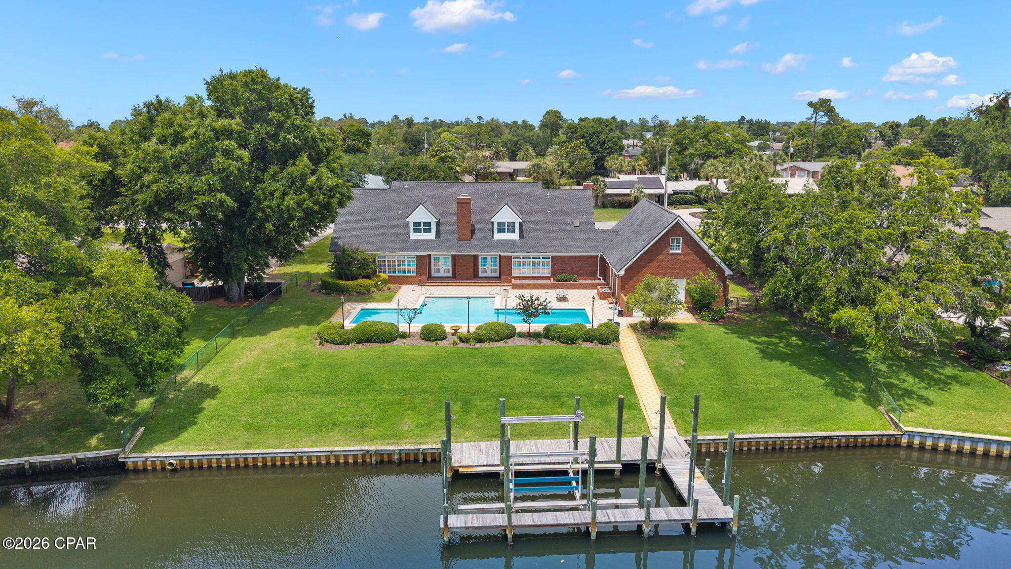 Nestled in the heart of Kings Point, one of Panama City's most storied and sought-after neighborhoods with NO HOA, this is an incredible WATERFRONT property where deep-water access, luxury amenities, and authentic community come together to make home. No HOA. This home is over 5,000 SF heated and cooled living space and has been designed for families who want everything within reach and ideal for those who want to truly live the lifestyle that waterfront living affords.

Step out your door, onto your private dock and oversized pool. Deep-water access paired with a 10,000 lb. boat lift with walk boards in a 34'x14' slip means your vessel is ready the moment you are, and with just 6 nautical miles to the Gulf of America with no idle speed zones, a saltwater escape is never more than a short cruise away. This dock is designed and prepped to add a boat house cover so when the time comes, you're ready to make it happen. When staying home is on the agenda, the pool draws you in: designed with lap lanes for the swimmer who takes their mornings seriously and transforms effortlessly into the ultimate backyard centerpiece. It's equally suited for quiet Sunday floats and back yard gatherings with neighbors you're going to love! 

A charming brick exterior, a covered porch the length of the home and mature landscaping is what you're greeted with when you pull into your two-car garage. Inside, every space has been sized generously and designed with intention. Oversized bedrooms and walk-in closets offers a home feel like a true retreat. The primary suite is anchored on the main level by two closets that rival entire rooms. A gracious sitting room off the foyer sets the tone from the moment you arrive. The dedicated home office, complete with its own fireplace and built-in with custom millwork, is the kind of space that makes working remotely feel like a privilege. And upstairs there's a flex room that would be equally suited as a private fitness studio, playroom, or creative haven, adapting naturally as your life evolves. Above the garage, an additional fully outfitted 720 SF (not included in overall SF) theater room doubles beautifully as an independent mother-in-law suite. A full bath is also accessible from this area giving your guests the space they deserve or perfect for nights in a game room. Mahjong or poker anyone?

The kitchen and living area are spacious and include exceptional views of the large pool, a pavered patio, mature landscaping and the waters leading into the Bay. The kitchen brings additional seating with an eat-in area and offers professional-grade appliances, a full-size wine cooler, double ovens-great for entertaining, cooktop with stainless range hood, ice maker, prep sink, and oversized walk-in pantry. The living area is anchored with a fireplace and flanked by two sets of French doors leading to the patio, pool and dock. The formal dining room is just off the kitchen and presented beautifully with a gorgeous chandelier and wallcovering. A convenient powder room for guests is located off the foyer in the center of the home. Upstairs, you'll find the flex room as well as two guest bedrooms with en-suite baths and multiple walk-in closets for each bedroom. This kind of space and room to spread out is rare in a home this size! 

Kings Point is the kind of community where people plant roots and stay. Walkable streets, mature canopy trees, and neighbors who wave...it's a pace of life that feels increasingly rare and genuinely worth savoring. The location is as practical as it is enviable: Publix and everyday conveniences are just minutes away. Coastal dining favorites in St. Andrews are just minutes away and the waterfront restaurants along St. Andrews Bay become part of your regular rhythm. Top-rated schools serve the area, and everything you love about coastal Florida living is right outside your door. Twenty minutes to the beach. Six nautical miles to the Gulf. Waterfront achieved!