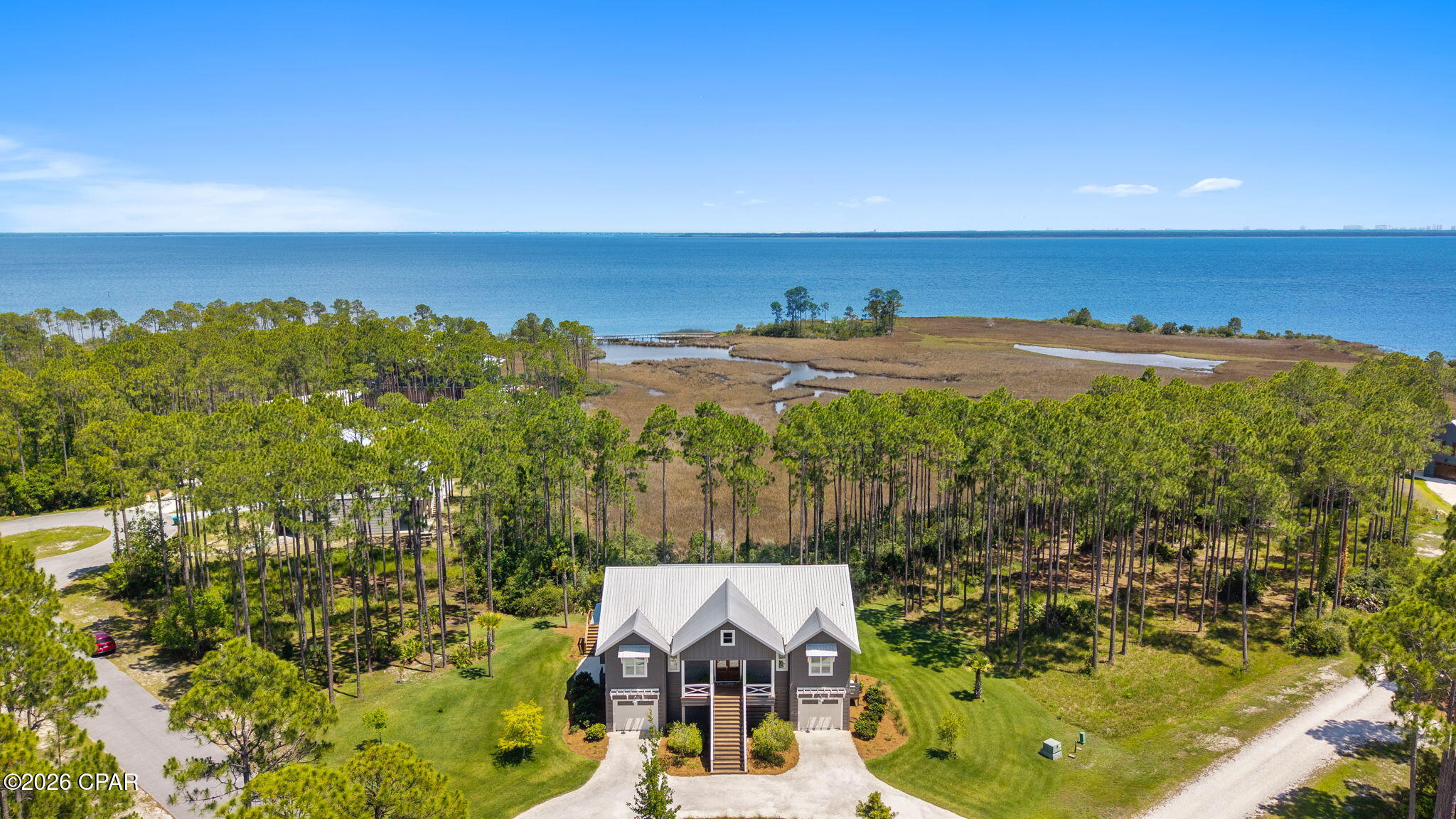 Overlooking West Bay with unobstructed water views, this custom-built residence is set on a premium 0.76-acre corner waterfront homesite with paved road access. The beauty of the setting extends indoors, where designer finishes and thoughtful details create a refined coastal home that feels both elevated and inviting. 

The kitchen serves as the centerpiece of the home, anchored by a Venetian plaster hood, Hallman Majestic gas range, quartz countertops, clay tile backsplash, open cypress shelving, and a dining nook featuring built-in bench seating with storage. A striking cypress beam connects the kitchen and living area, where a Venetian plaster fireplace serves as a focal point against a backdrop of sweeping water views.

Designed as a true retreat, the primary suite features scenic water views. The adjoining bath features Carrera marble finishes, polished nickel fixtures, an oversized glass shower and a freestanding soaking tub. Dual custom closets, including a dressing area with built-in vanity complete the suite. 

The expansive screened porch, complete with a gas fireplace, provides a breathtaking setting to relax and take in the views of West Bay. Thoughtfully designed landscaping complements the home's natural surroundings, with ample room for a future pool or addition. Additional features include an elevator, impact-rated windows, EV charging station, whole-home Generac generator, and finished split garages with abundant storage.

RiverCamps offers a lifestyle unlike any other along the Emerald Coast. This private, gated waterfront community is bordered by West Bay and Crooked Creek, providing direct boating access to Shell Island and the Gulf. Residents enjoy dry boat storage, a community boat launch and day-use slips, a resort-style pool and pavilion, a 600-foot pier, miles of scenic trails and boardwalks, and a fitness center coming soon. Ideally located just minutes from Northwest Florida Beaches International Airport, Pier Park, and the area's white-sand beaches.