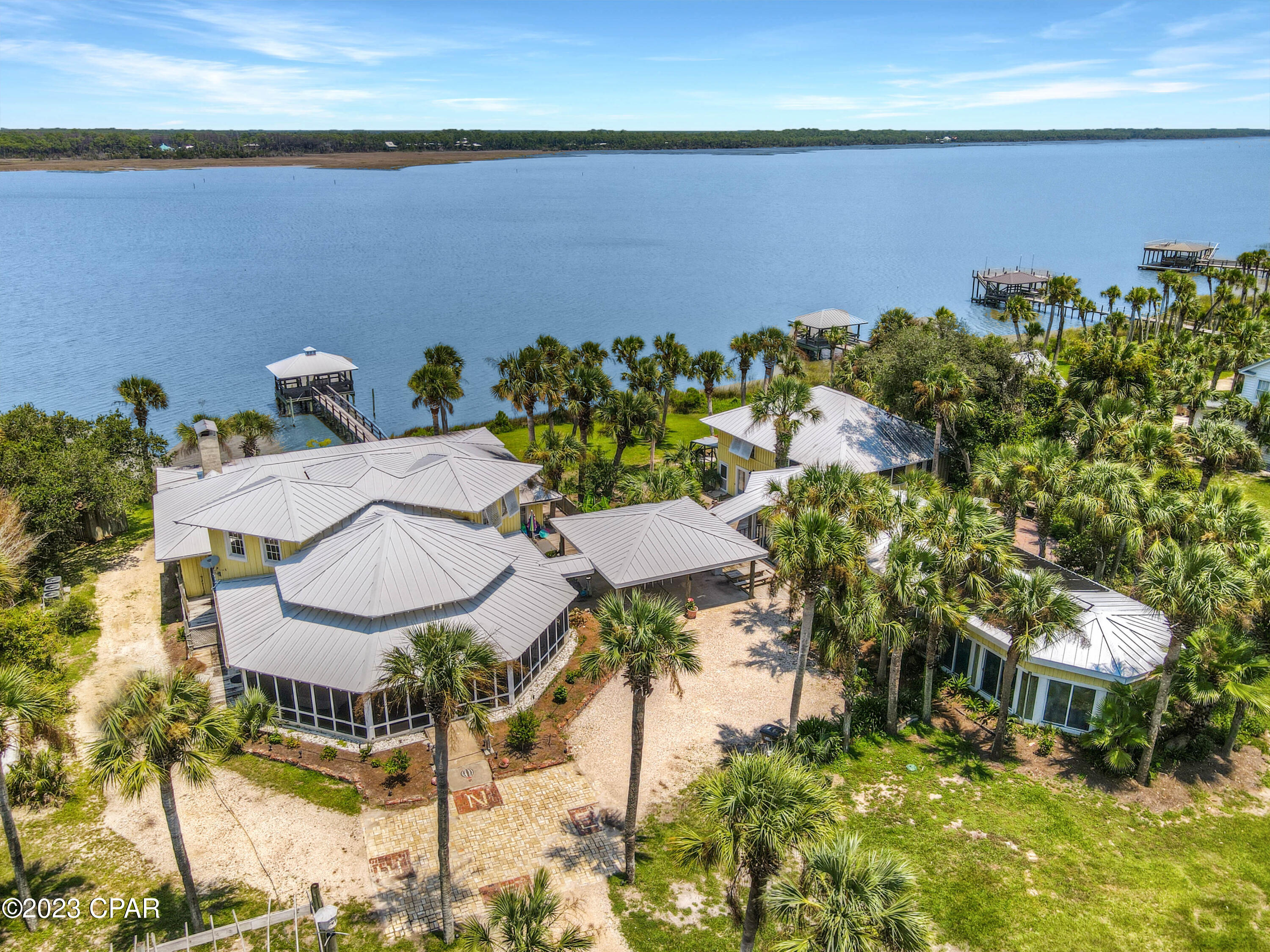 Step into the enchanting world of ''THE GROVE'' at Indian Pass and embrace the true essence of ''The Forgotten Coast.'' This captivating retreat is nestled on approximately 3 acres of pristine land, stretching along the serene Lagoon of Indian Pass. With stunning Bay and Gulf Views, this estate offers an authentic ''Old Florida'' experience, where timeless charm meets modern-day luxuries, creating unforgettable memories. If you crave seclusion and tranquility, this tropical paradise is a hidden gem. Discover over 200' of panoramic Lagoon views, providing an idyllic setting for relaxation and rejuvenation. The shallow water dock beckons you to indulge in fishing and exploration of the picturesque waterways. With 3 separate houses on the property, totaling 9 bedrooms, 6 bathrooms, and 2-½ baths (the main house has 5BD/4.5 BA, the upper bungalow is a 3/2, and the lower bungalow is a 1/1), this estate offers ample space for your family and guests. Step inside and be captivated by the charming fishbone hardwood floors, original shiplap, and unique custom bunk beds, adding character and allure to this 1920's home. In the chef's kitchen, your culinary passions will be fulfilled with double appliances and stone countertops, ensuring that cooking is effortless. Large wrap-around screen porches, sunrooms, and lovely terraces invite you to unwind and immerse yourself in the serene surroundings. The lush gardens enhance the enchanting beauty of this extraordinary estate. Entertainment awaits in the game room, featuring a dry bar, pool table, and an indoor heated pool, allowing relaxation regardless of the weather outside. Throughout the property, you'll be captivated by the rich history and stories behind this unique home, adding a touch of nostalgia to the overall experience. This property is a place where time stands still, and cherished memories are waiting to be created.