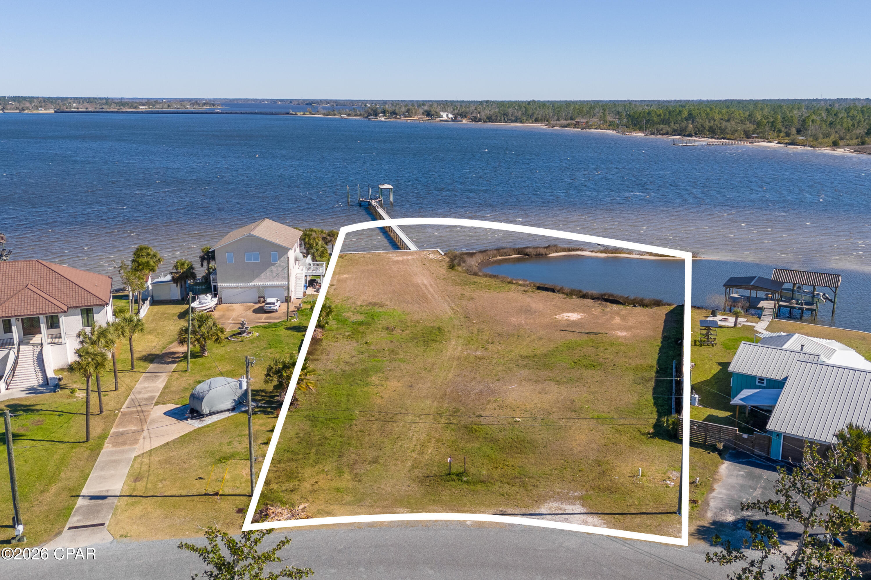 A rare stretch of North Bay shoreline sets the stage for something extraordinary. Two lots together, Spanning 1.2 acres with an impressive 222 feet of deepwater frontage, this offering presents a remarkable canvas for a custom waterfront estate defined by space, privacy and possibility. A solid seawall is already in place, along with a large private dock and boat slips, allowing you to step straight into the bayfront lifestyle from day one. Launch at sunrise, cruise at sunset or simply let the rhythm of the water shape your days. With deepwater access, boating enthusiasts will appreciate the freedom and flexibility this setting affords. What truly distinguishes this property is its own small island feature, creating a natural buffer and a protected cove feel just off your shoreline. The result is a uniquely intimate waterfront experience, where calm waters and wide open bay views exist in perfect balance. It is a setting that feels both expansive and tucked away, offering room to design a legacy home with sweeping outdoor living spaces, a resort-style pool or lush coastal landscaping framed by panoramic water vistas. Located in College Point and near Isaac Bird Park, this homesite pairs serene bayfront living with convenient access to green space and recreation. Properties with this much frontage, acreage and character are increasingly scarce. Here, the foundation for your vision is already in place; all that remains is to bring it to life.