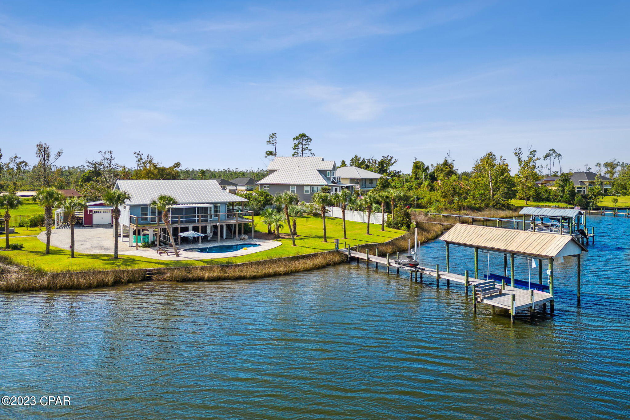 Gorgeous waterfront home that's as close to paradise as you can get.  As you enter through your private security gate fresh beautiful landscaping abounds with breathtaking views of the deep waters of Cook Bayou and East Bay. Along with the views is your own private salt water pool that adds a spa like serenity to this little piece of paradise.  Entering the home, you will immediately notice the bright open floor plan of the living room, kitchen and dining area. The soft wall colors, natural light and beautiful tongue in groove ceilings create a relaxing environment that makes this cozy home feel comfortable and inviting.  Prepare your meals in the beautiful, as well as functional kitchen while admiring your waterfront view.  The large primary bedroom has sliding glass doors that lead out to the balcony and screened in porch that overlooks the bay and pool.  The primary bathroom will take your breath away with its spa like feel, with glass walls, double vanity, and tiled shower.  On the way to the dock, you will find the recently added 12,000 gallon salt water heated pool with water feature and LED lights.  Continue down the composite wood dock to find the covered boat lift with electric motors and a newly installed jet ski lift.  Imagine ending your day relaxing on the custom-built bench at the end of the dock watching the dolphins play and birds feed as the sun sets and delivers an unimagined beauty. Every upgrade in this home was carefully thought out and designed for efficiency, functionality, and energy savings from the seamed metal roof to the Bosch air conditioning system. Large oversized work shop with electricity and a lean-to on both sides is great for the hobbyist or craft enthusiast.  If you're looking for beautiful property that provides amazing access to water sports and some of the most stunning sunsets around, then you have found it.